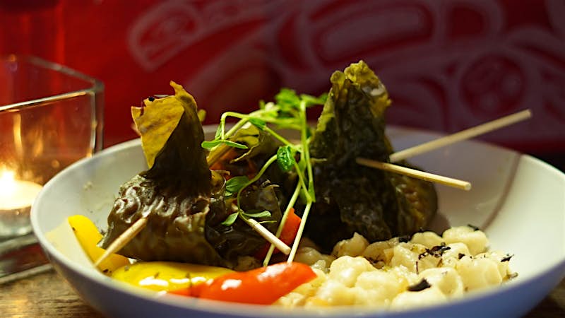 A pair of green dumplings sit in a plate of vegetables; Indigenous food