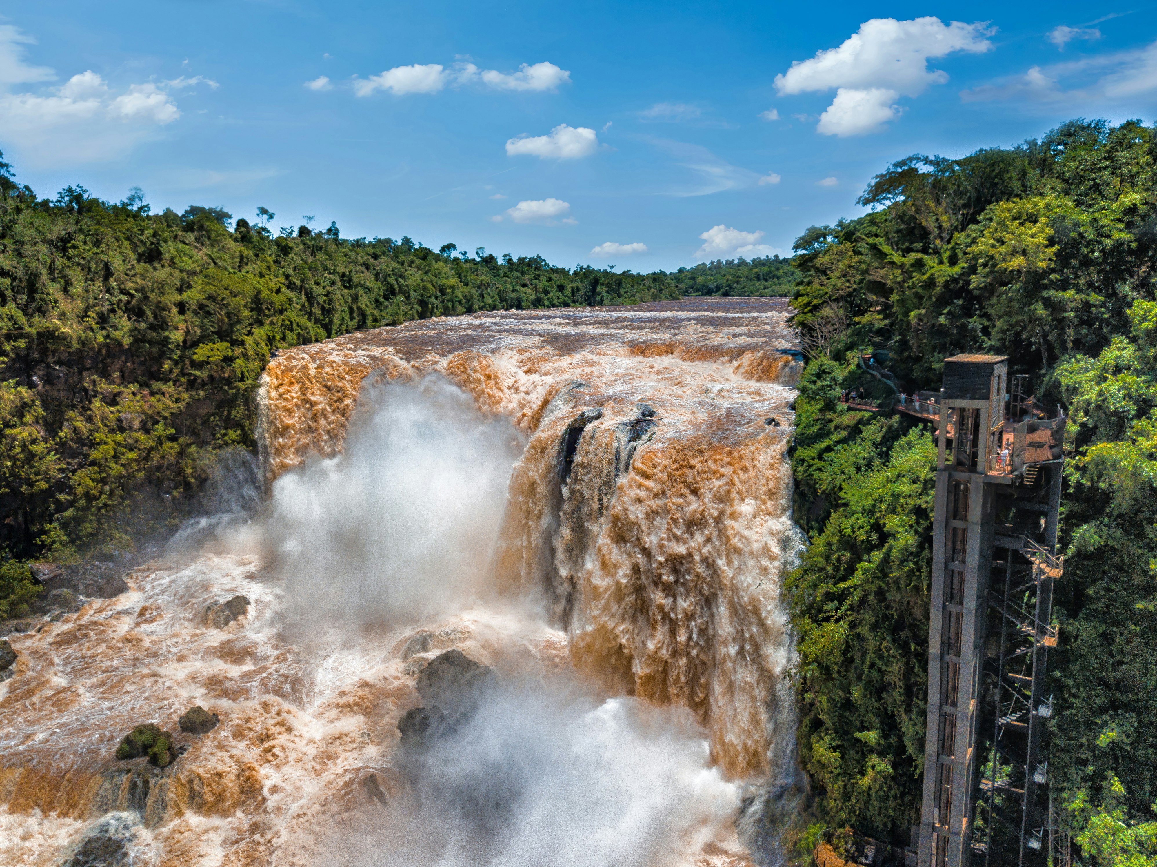 Brown colored water rushes over a tall falls in near the city of Ciudad del Este in Paraguay