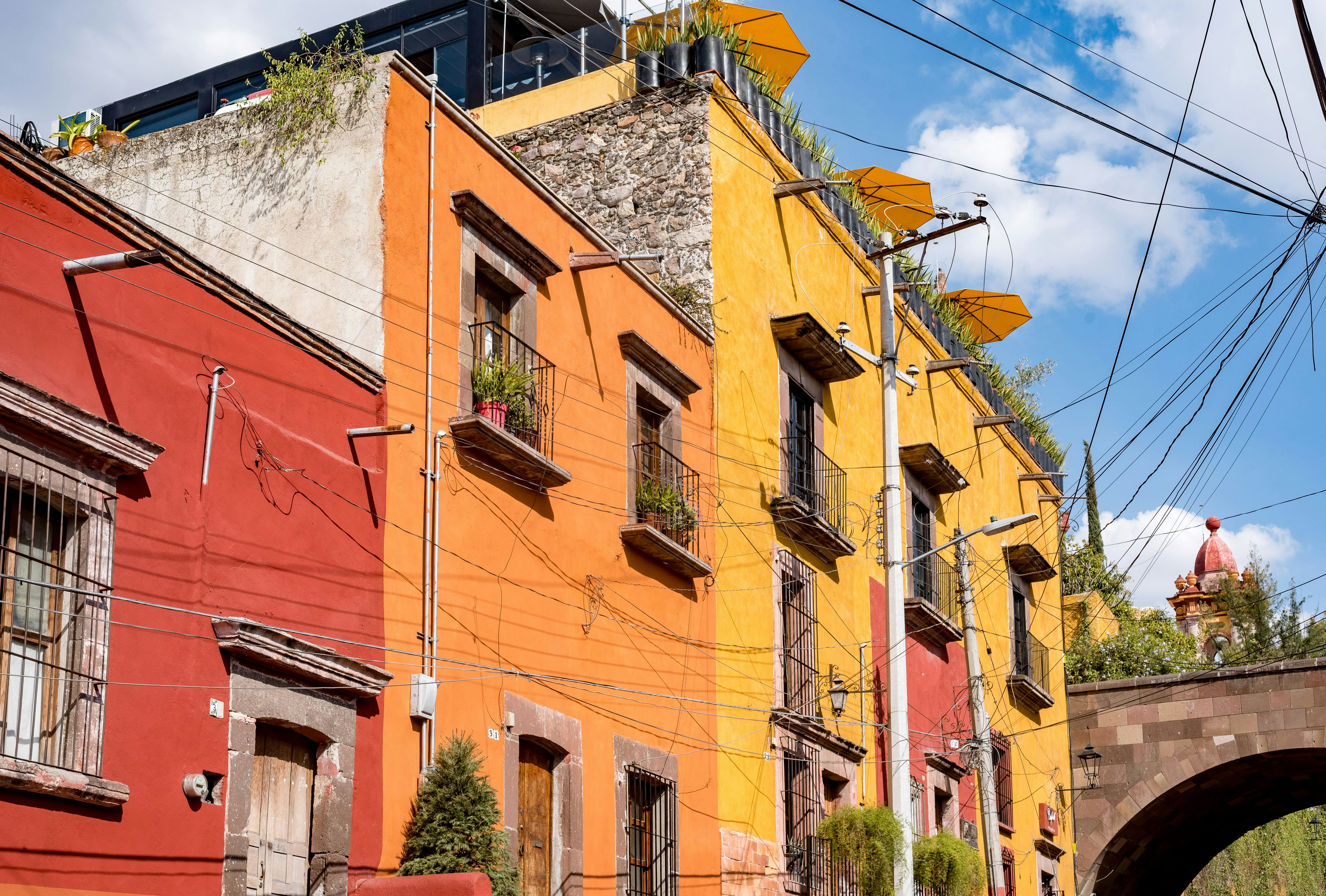 Röda, gula och orangea byggnader under en blå himmel i den mexikanska staden San Miguel de Allende 