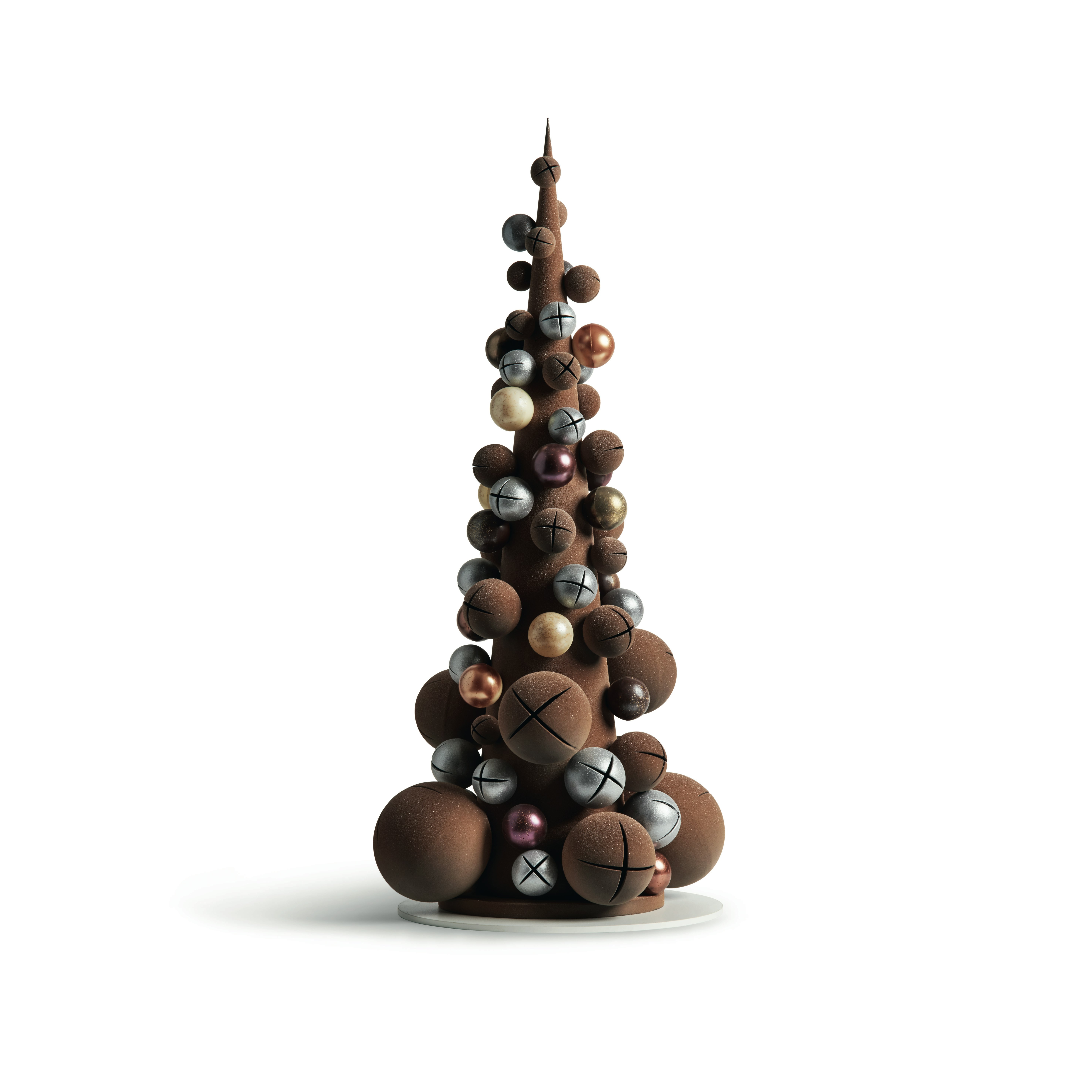A tall, narrow Christmas tree constructed of chocolate balls and silver and gold jinglebells sits on a thin white platter against a white backdrop