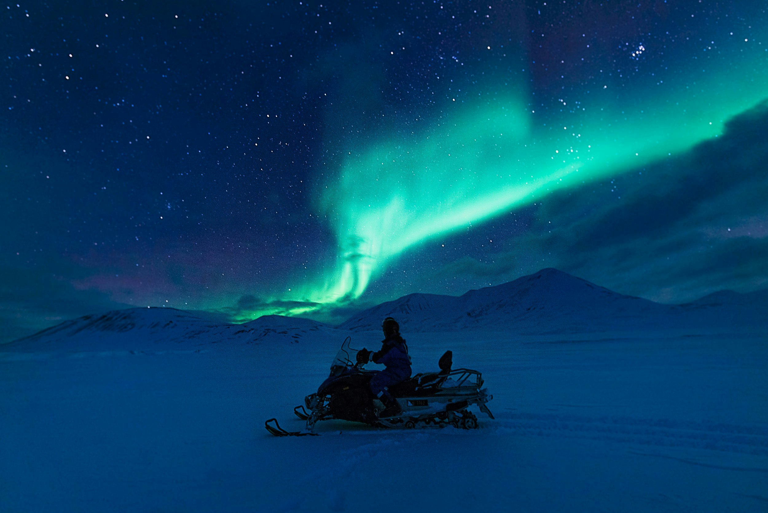 A person on an electric scooter with the Northern Lights in the background