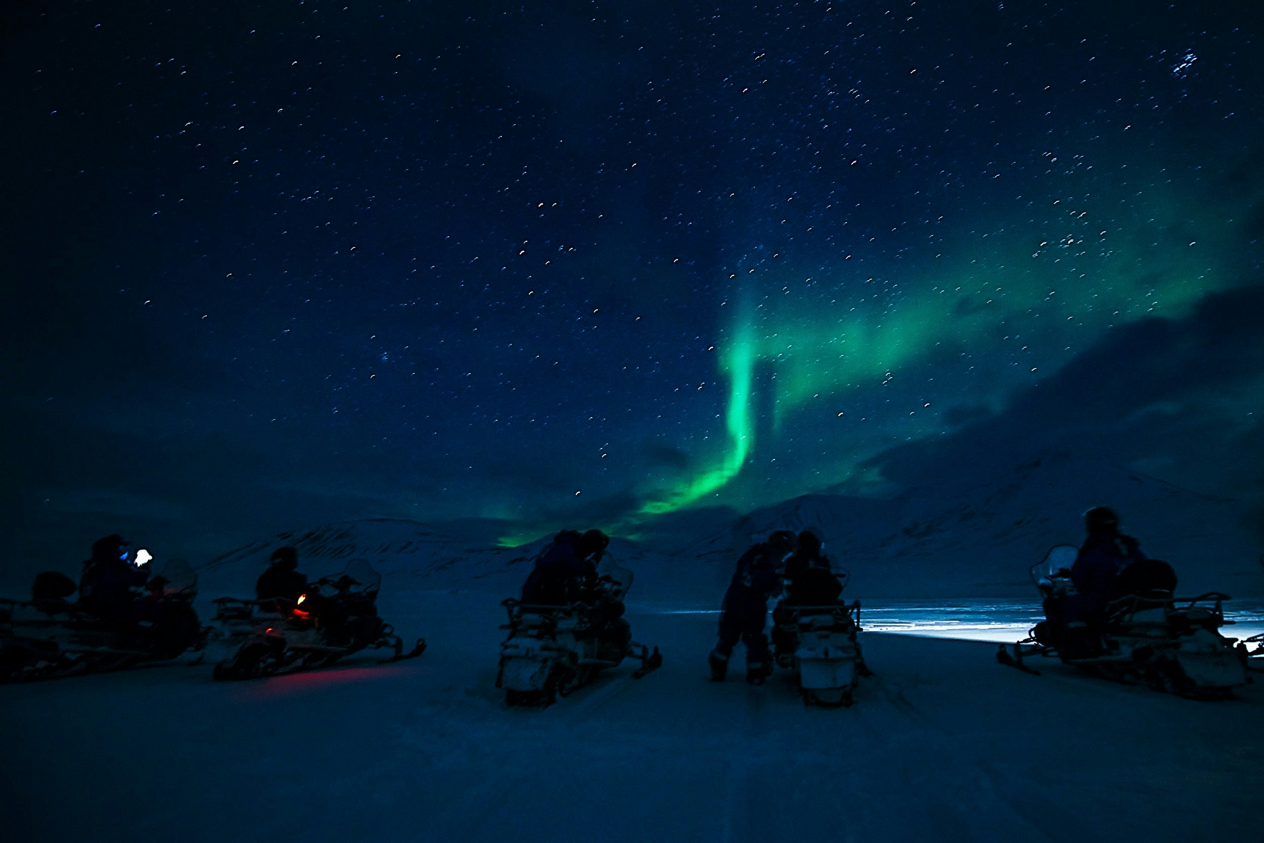 People on electric scooters with the Northern Lights in the background
