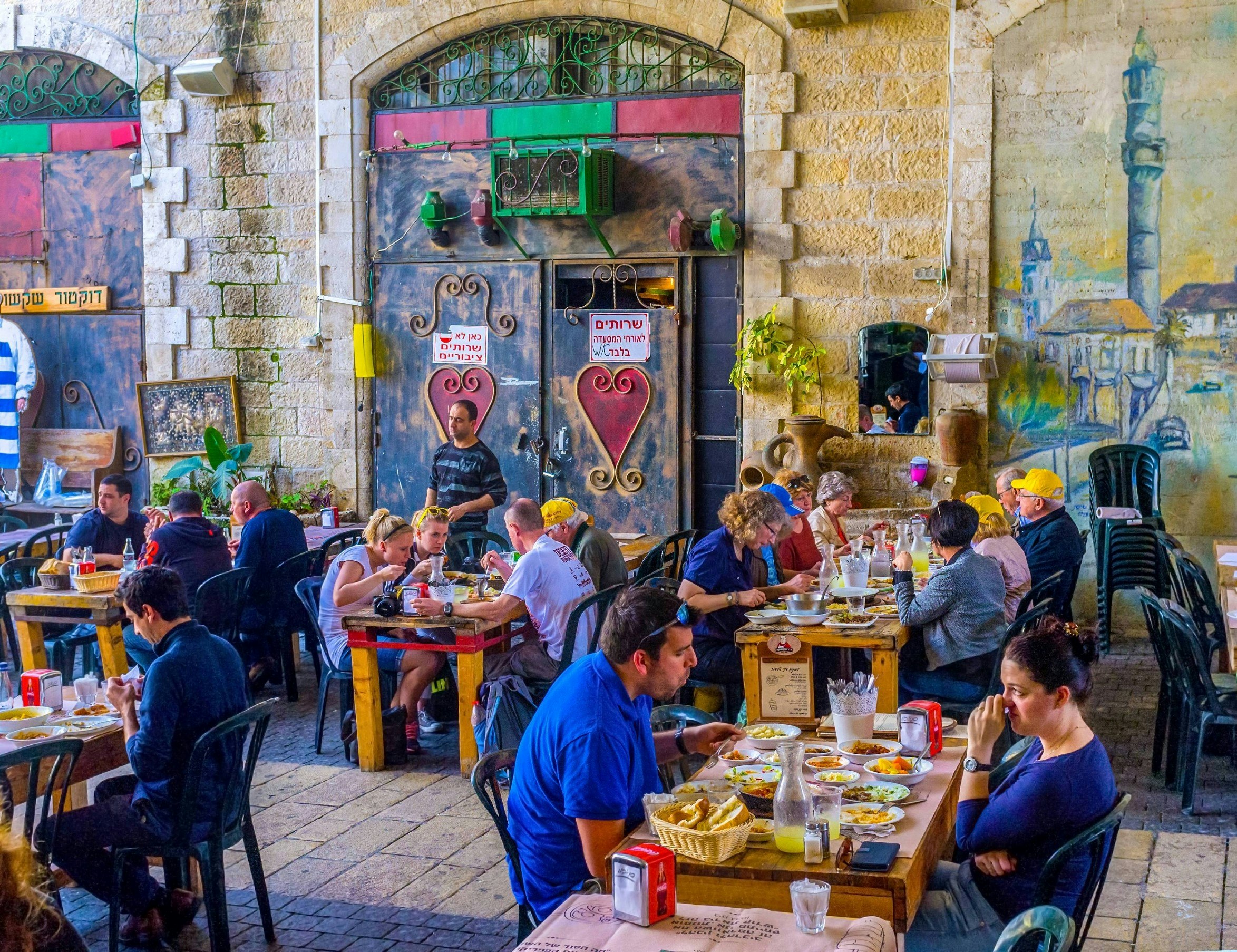 Tables full of people are enjoying food in a Tel Aviv restaurant 