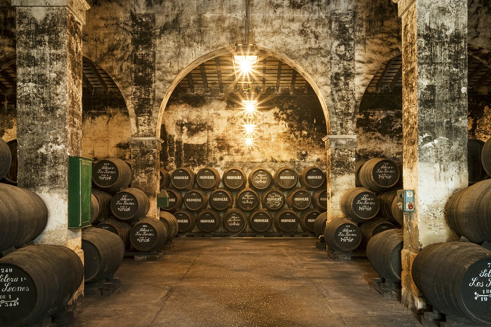 Black barrels full of sherry line the walls in a stone cellar. Cádiz, Spain.