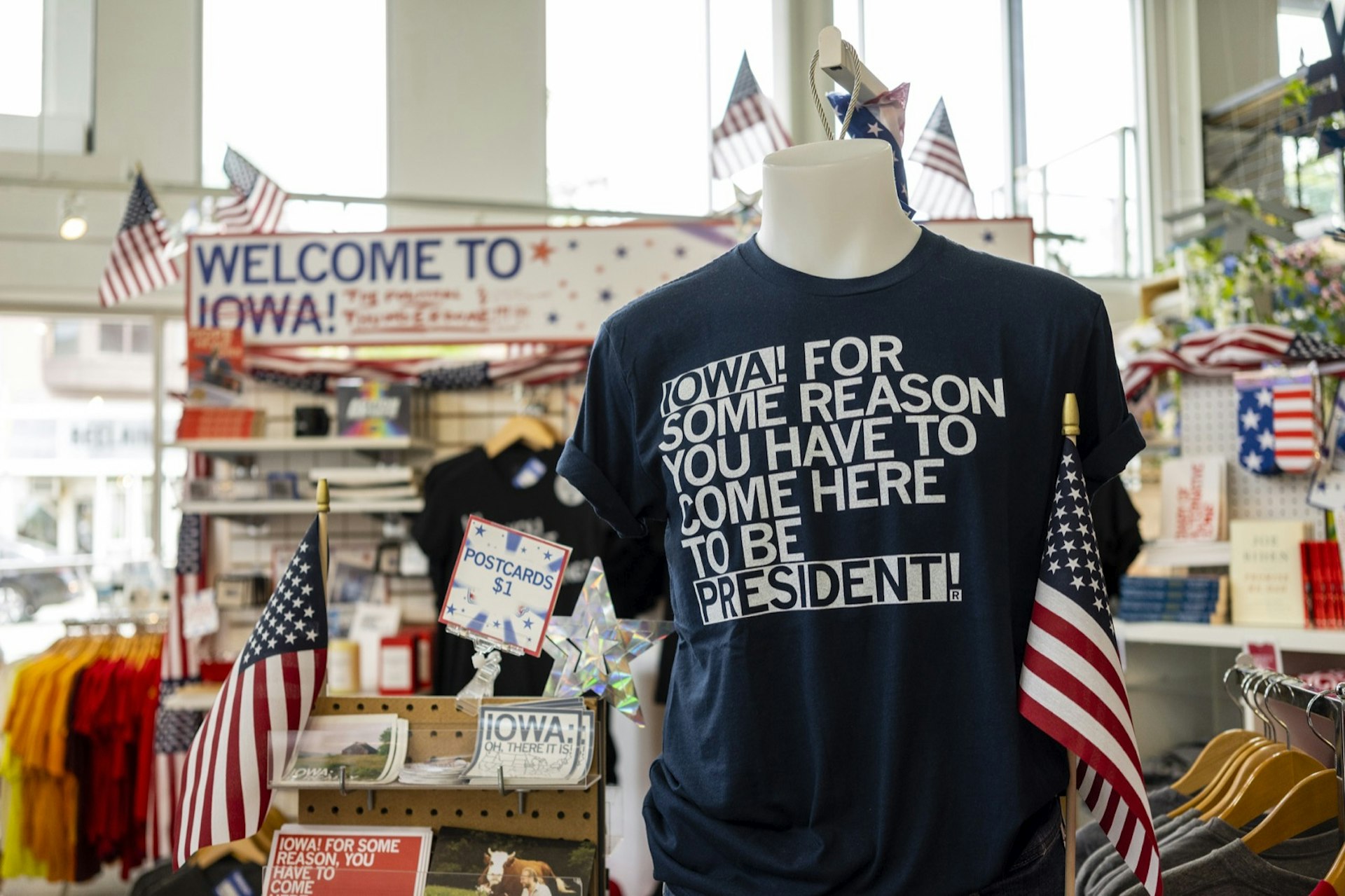 A black t-shirt on display reads, "Iowa! For some reason you have to come here to be president!" at a shop; Things to do in Des Moines during the Iowa Caucuses