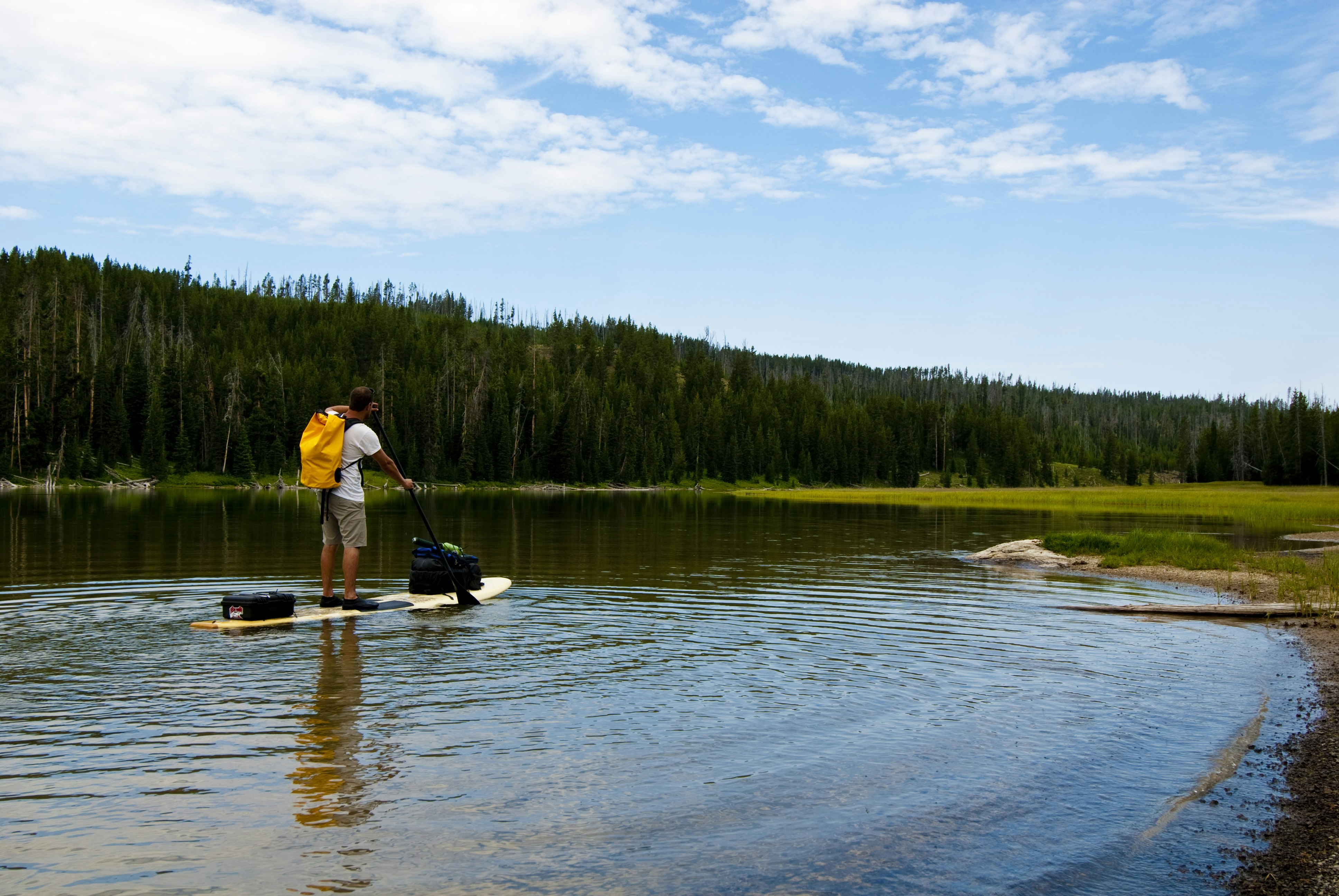 A stand-up paddleboarder on a lake in Yellowstone National Park