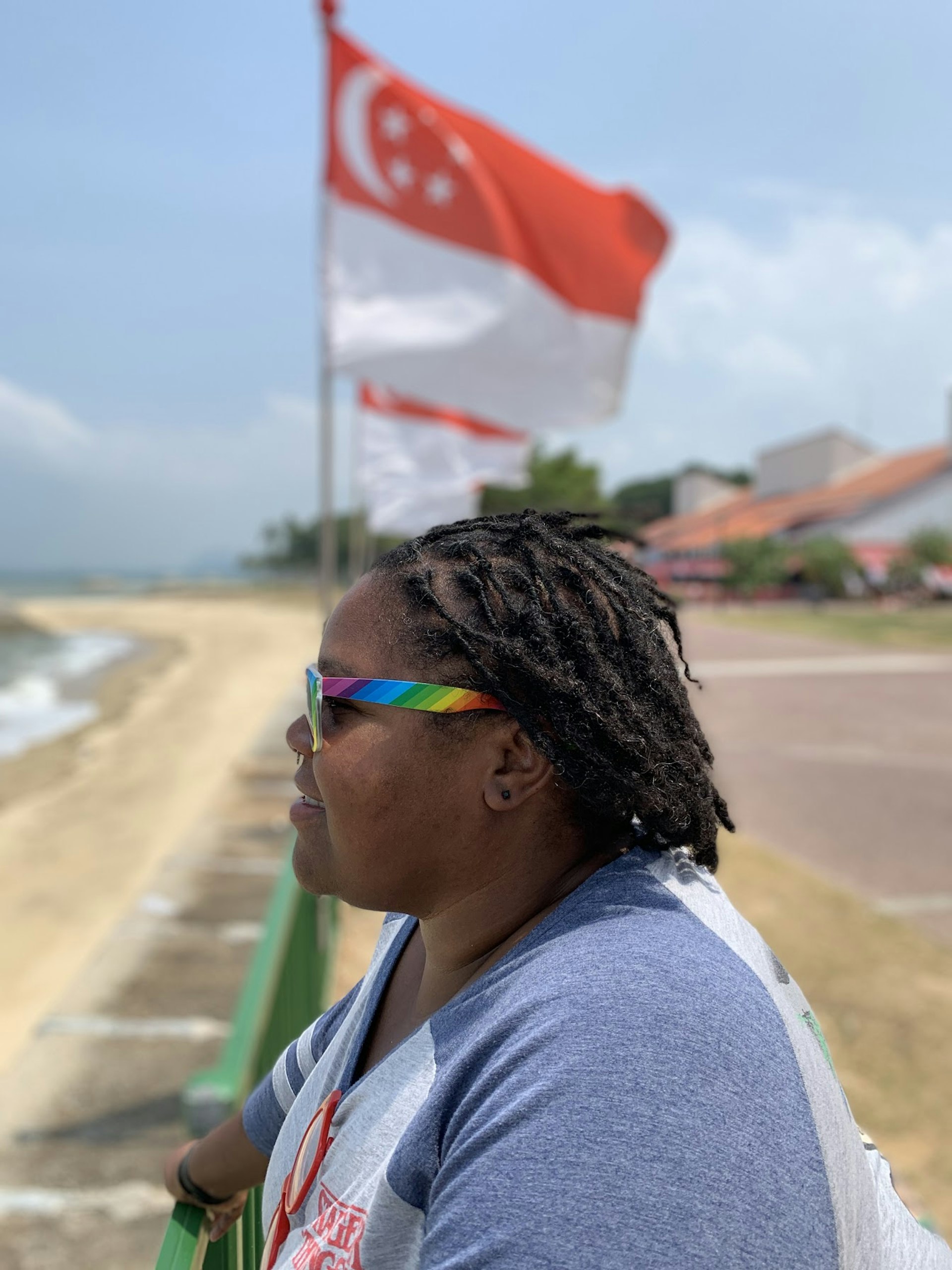 Profile of a woman's hair blowing in the wind as she stands on a beach. In the background a red and white flag flutters in the wind; traveling after pulmonary embolism 