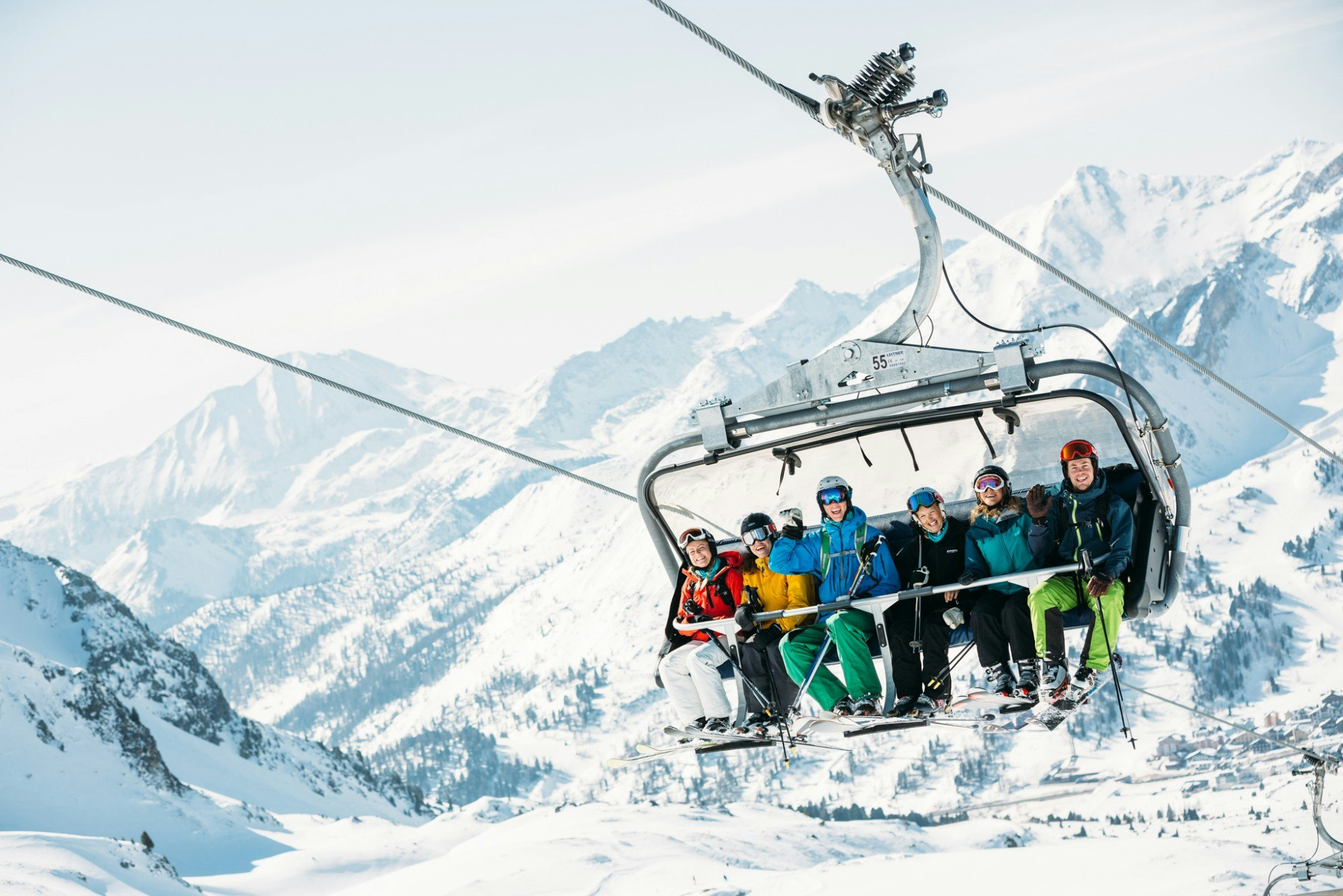 Six people being transported in a ski lift over a snow-covered landscape