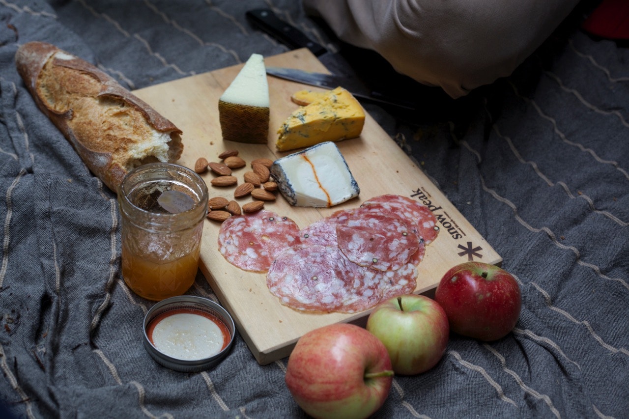 Snow Peak cutting board set on a picnic table with a snack spread