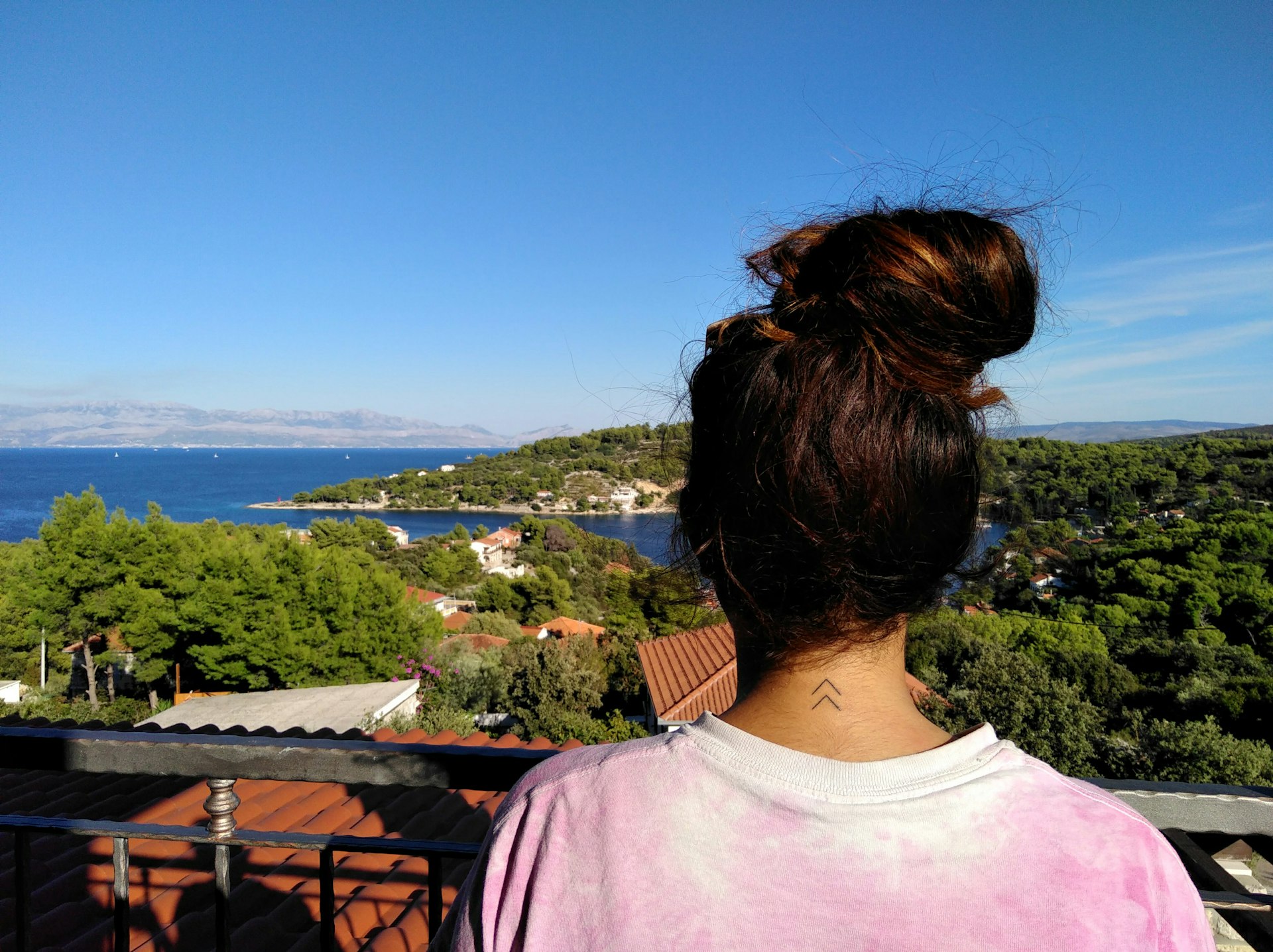 Writer Christina Webb with her back to the camera, gazing out to sea from Croatia's Šolta Island.