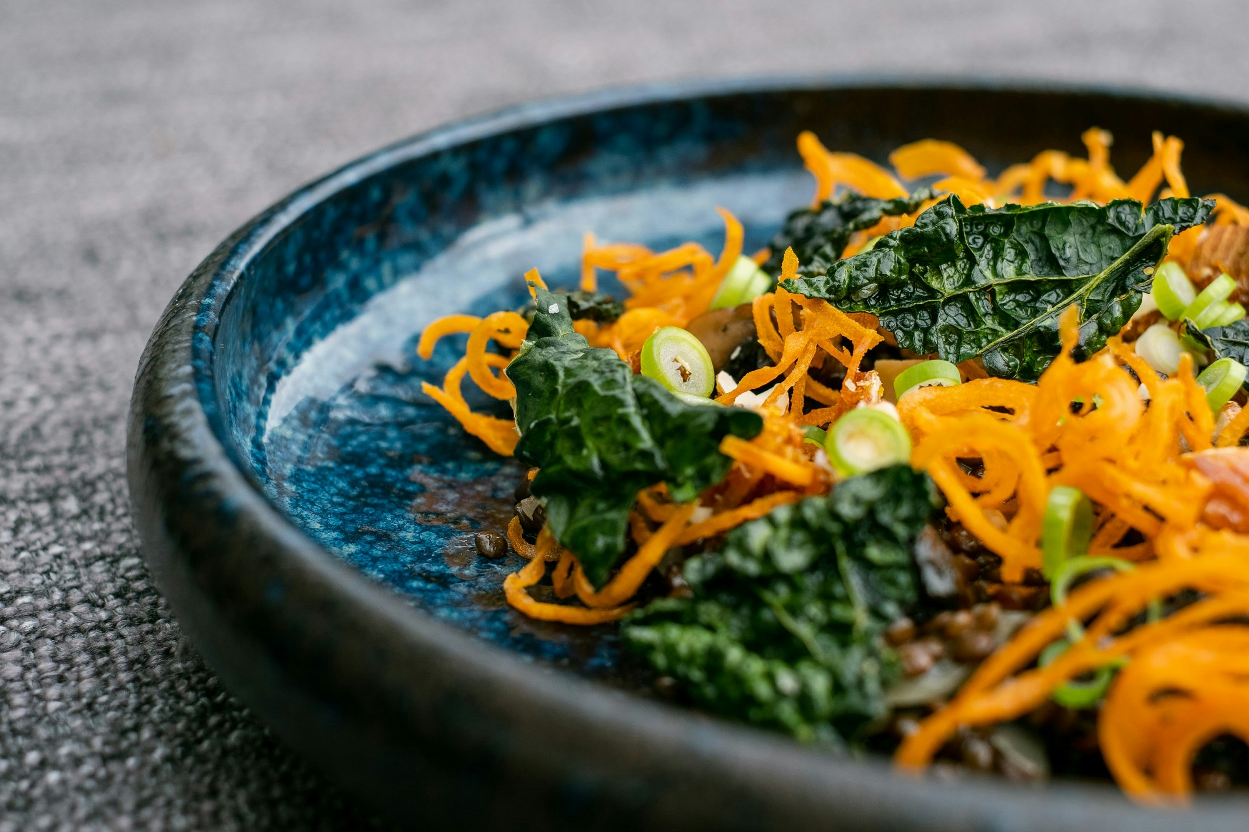 A bowl of kale, swirled carrot and green onions