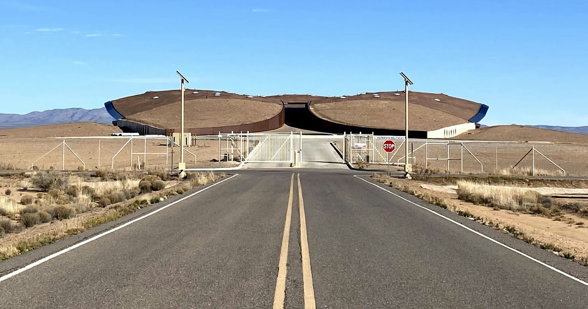 A road leads to a flat, turf-roofed building that looks like an alien spaceship