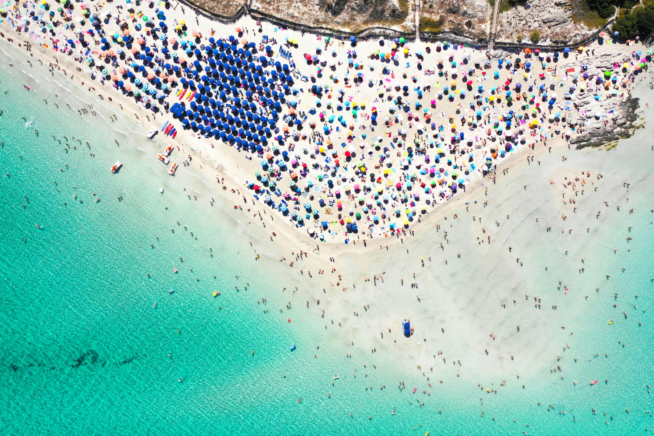 Bird's eye view of Spiaggia Della Pelosa packed with beach towels and umbrellas