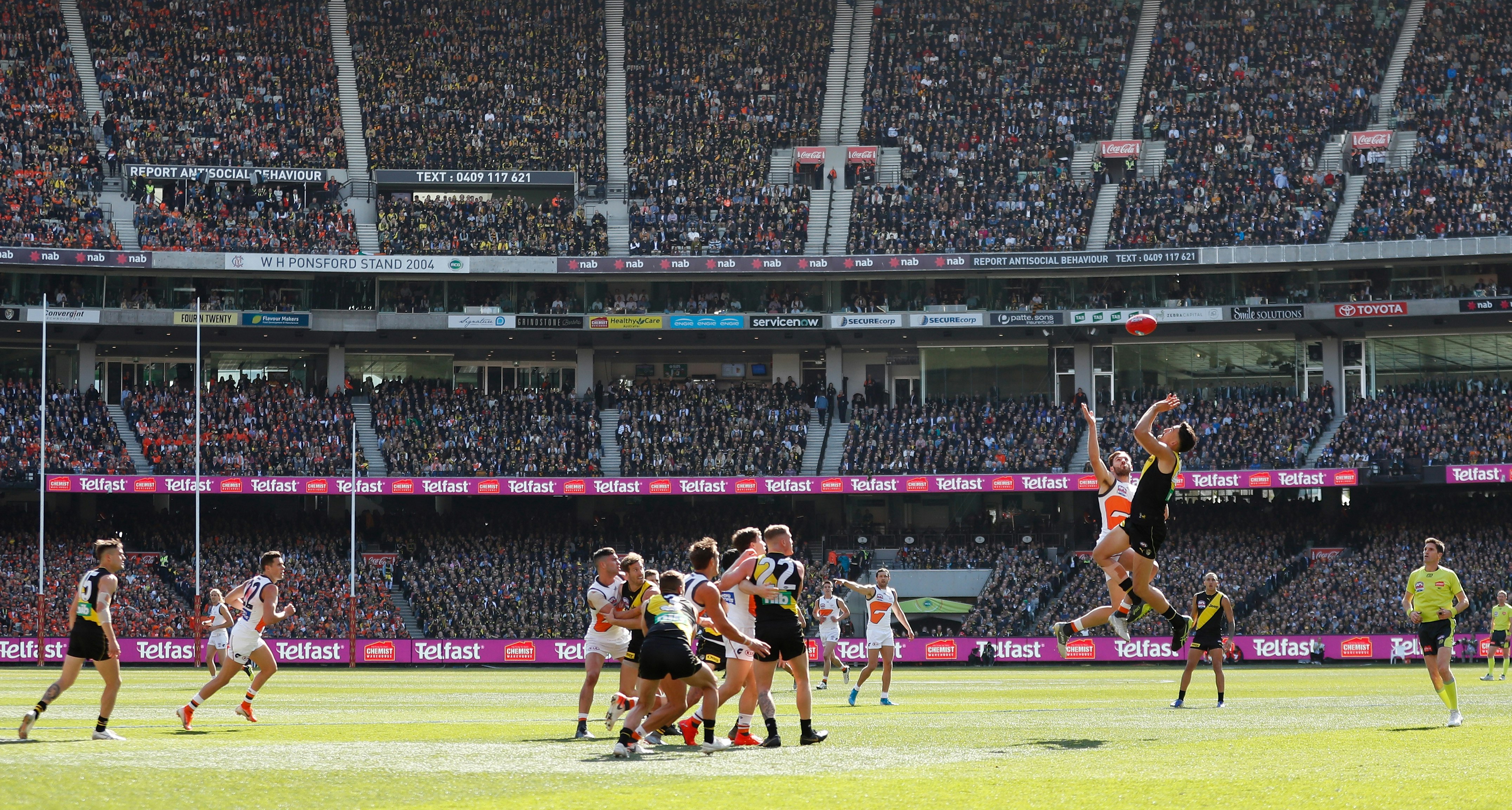 Stands full of spectators watch two teams competing in Australian Rules Football at the MCG in Melbourne.
