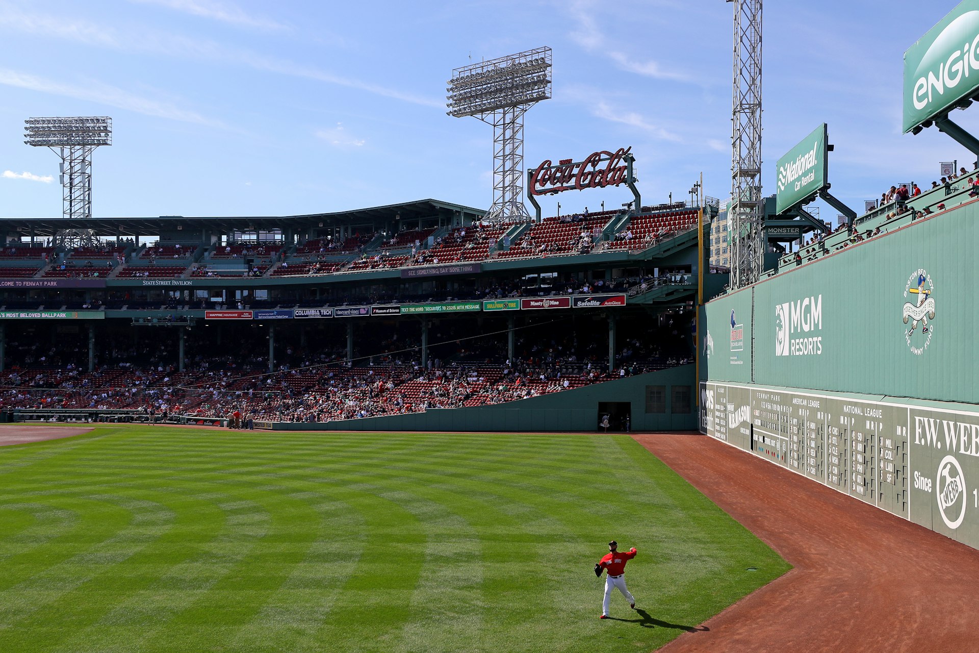 A baseball player fields a ball next to the large wall called the Green Monster in Fenway Park, Boston