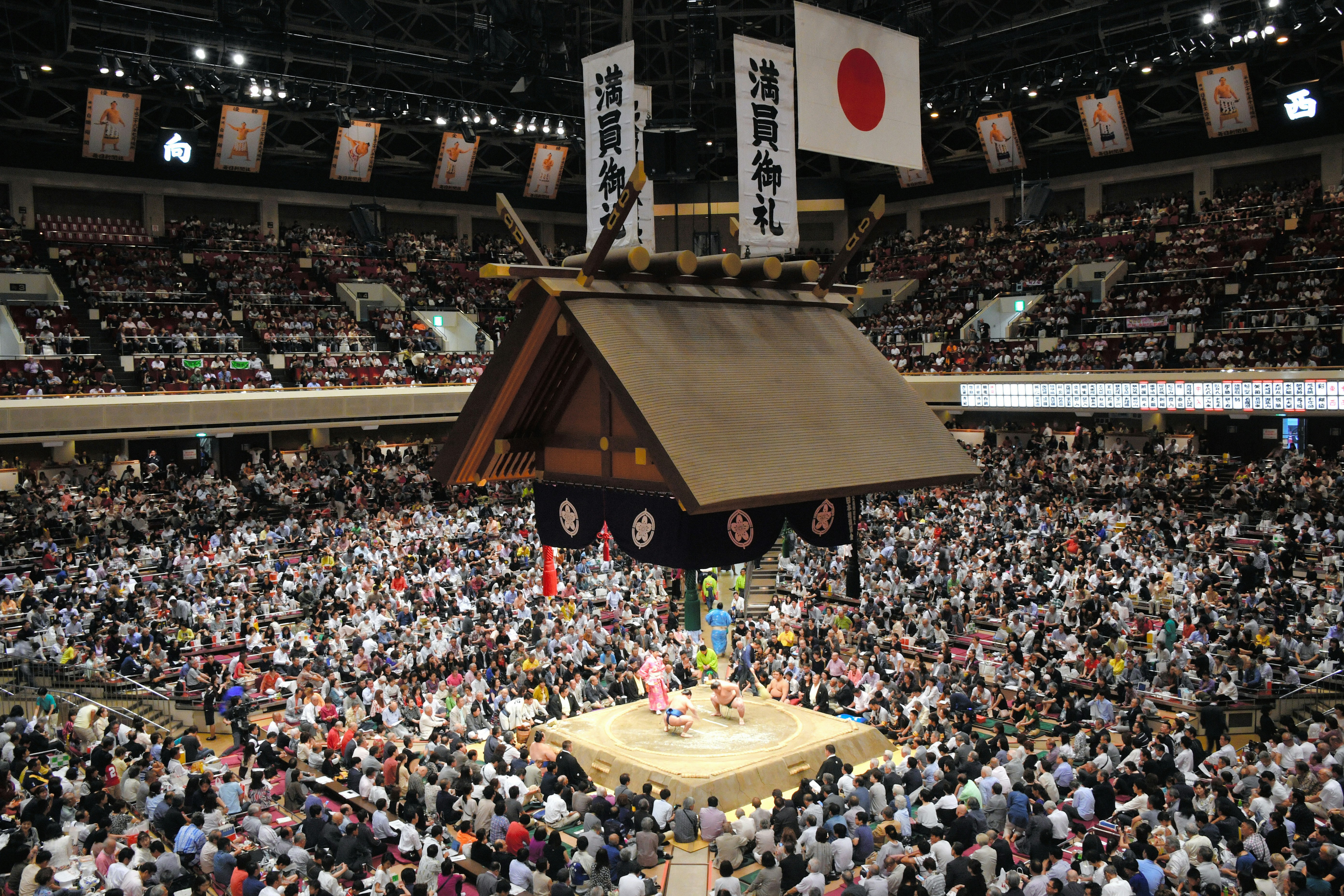 Spectators watch two sumo wrestlers competing at Ryōgoku Kokugikan, Tokyo