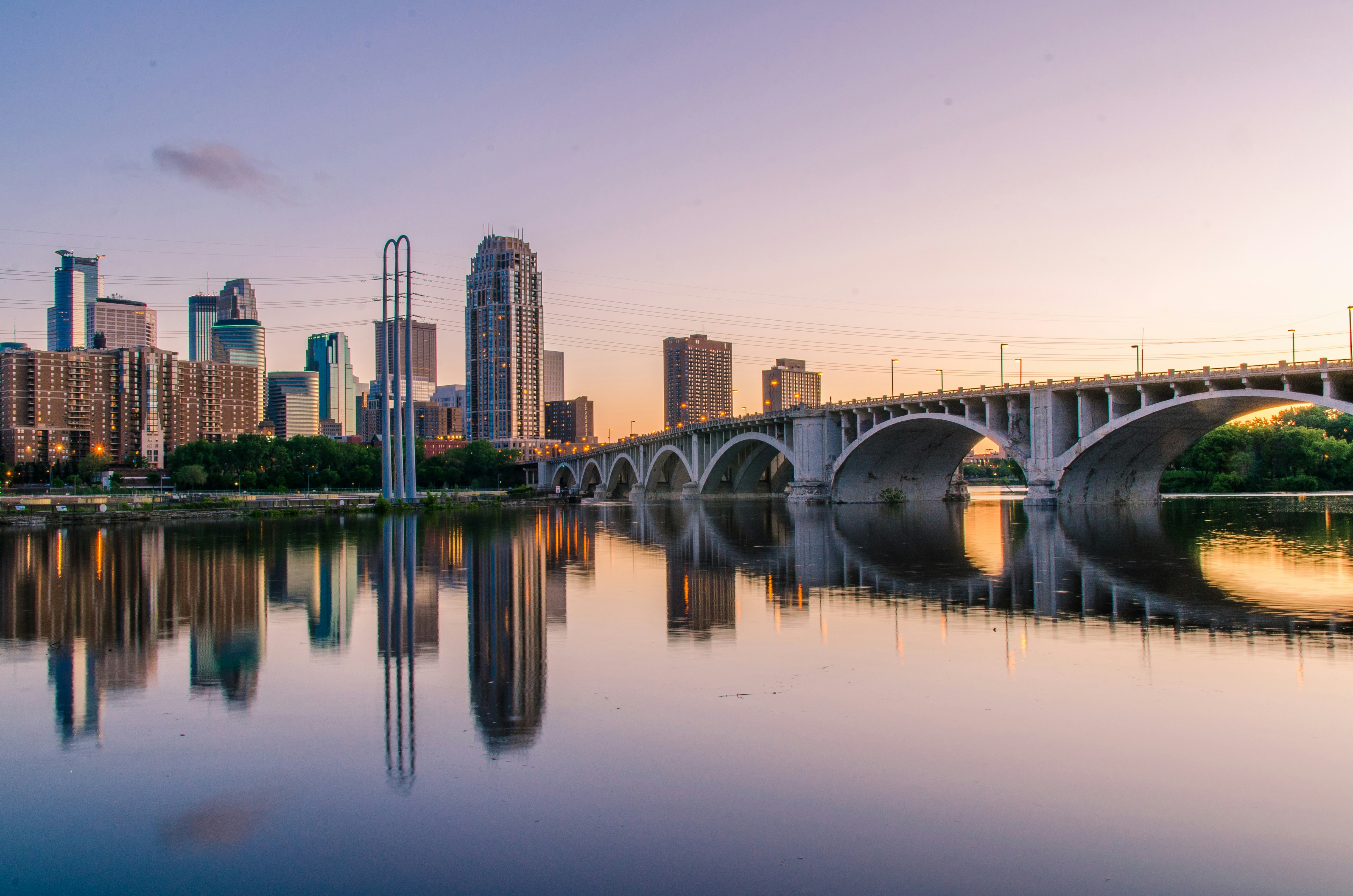 A bridge over calm waters reflecting the Minneapolis skyline