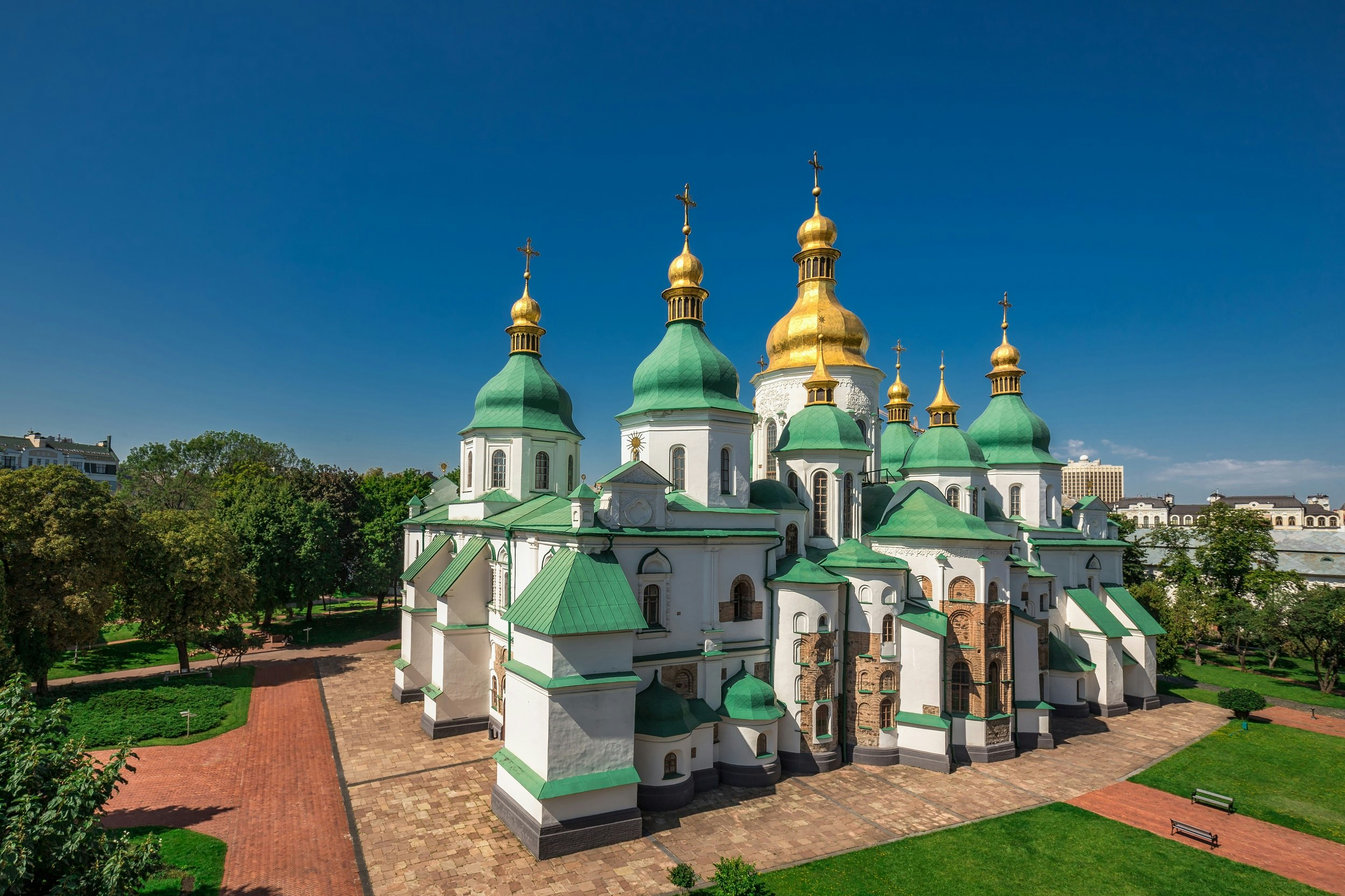 A large cathedral with domed green roofs with one large gold dome in the centre