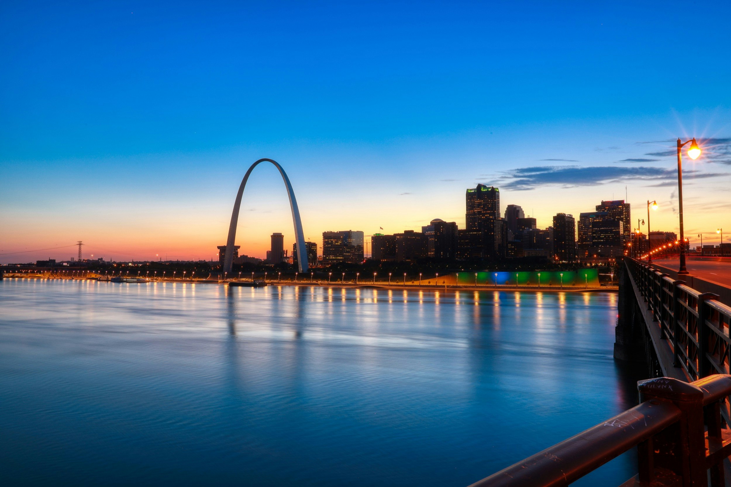 En solnedgång reflekteras i Mississippifloden när St Louis skyline och Gateway Arch visas;  Sevärdheter utanför allfartsvägarna i St Louis