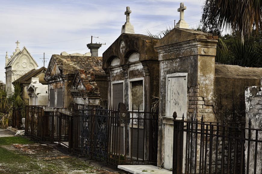 A line of decaying mausoleums sectioned off by rusty gates in the St. Louis Cemetery; us haunted places 