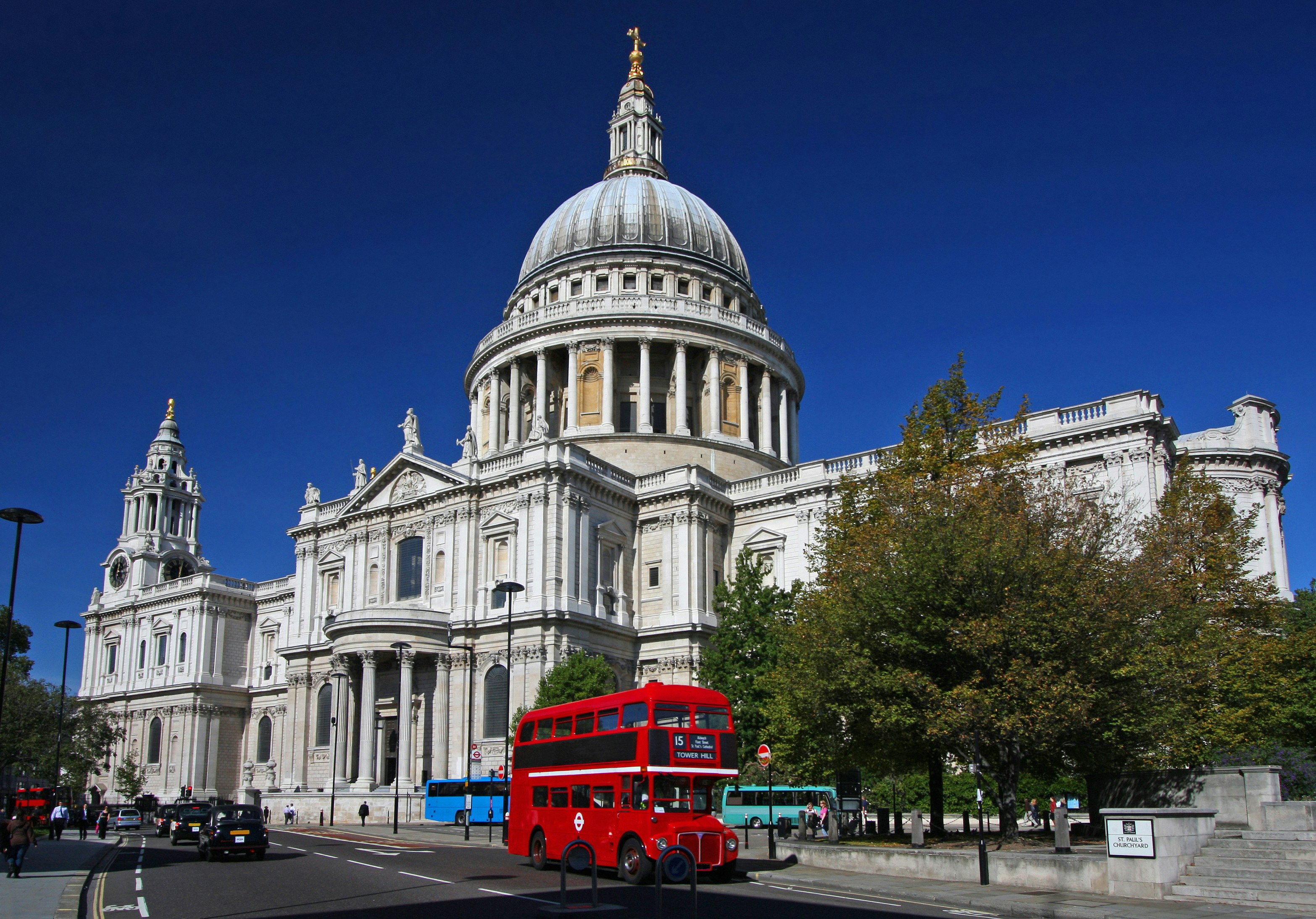 A red double-decker bus rolls past the white-washed, stone, domed St. Paul's Cathedral; Heathrow layover