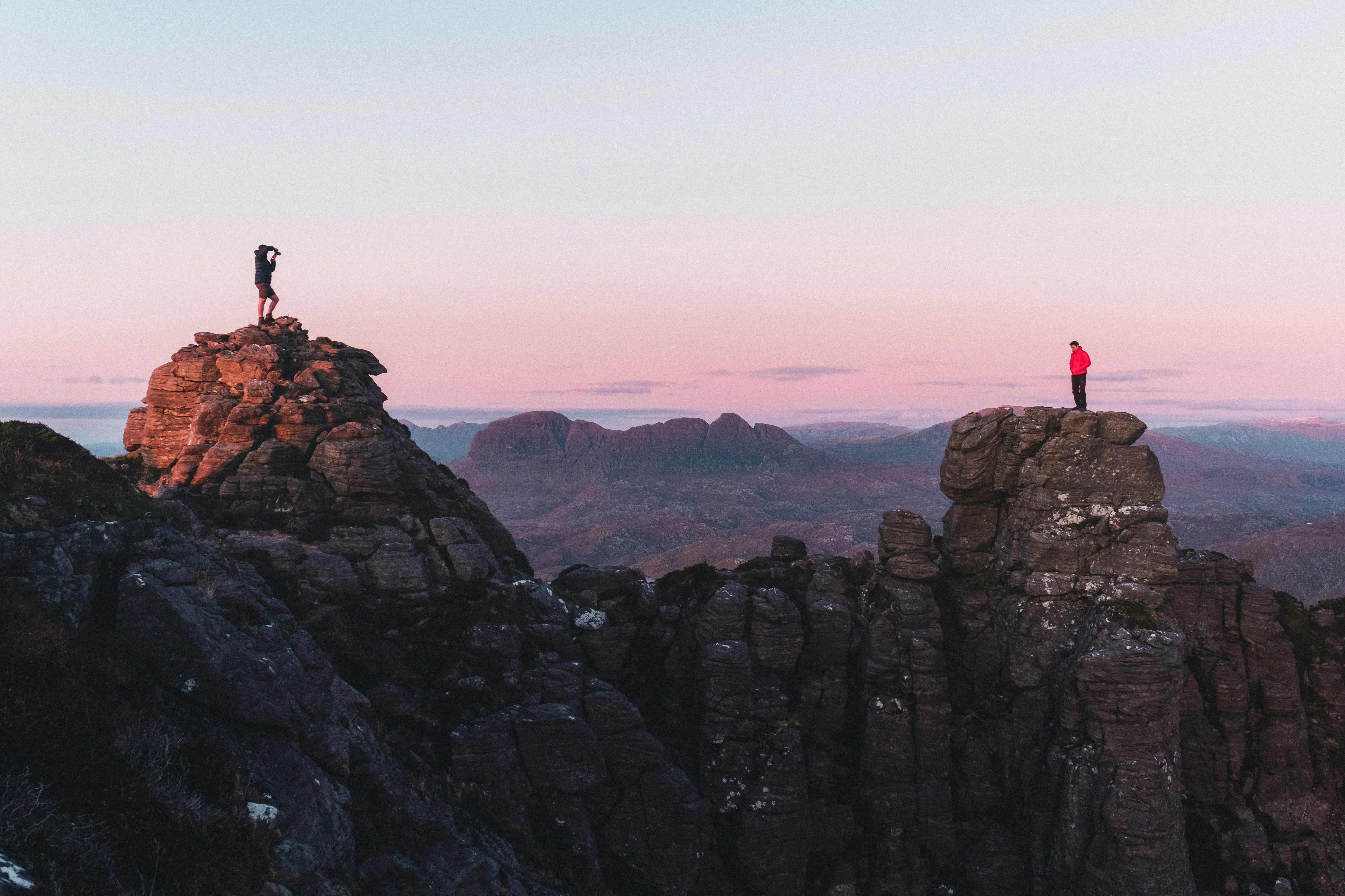 Stach Pollaidh at sunset, with two men standing on separate peaks. 