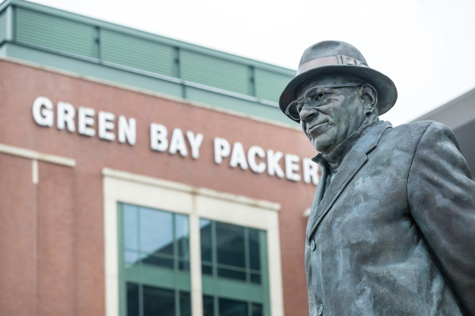 A statue of Vince Lombardi in front of a sign reading "Green Bay Packers"