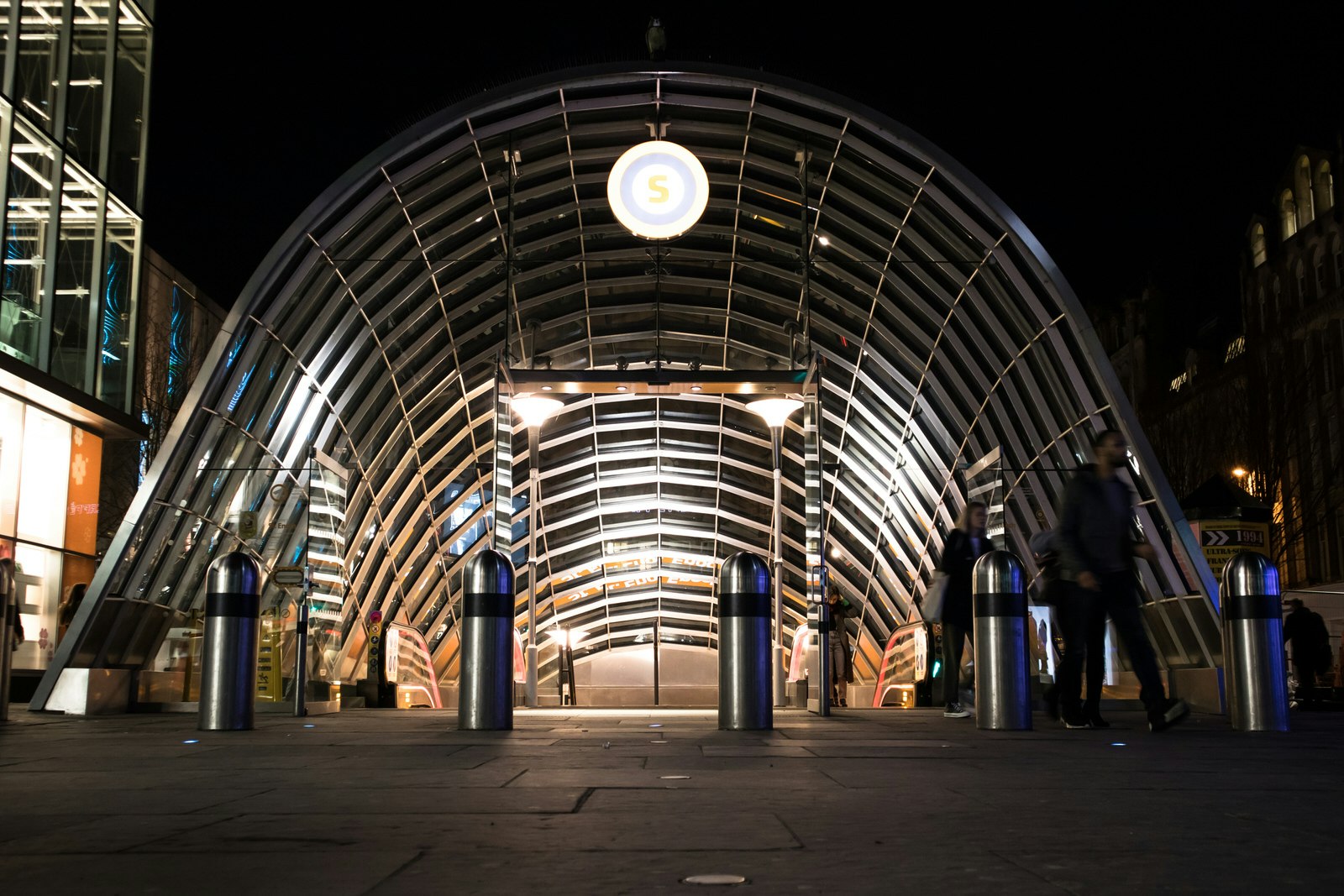 Exterior night shot of the illuminated entrance to St Enoch Subway station on Argyll Street, Glasgow