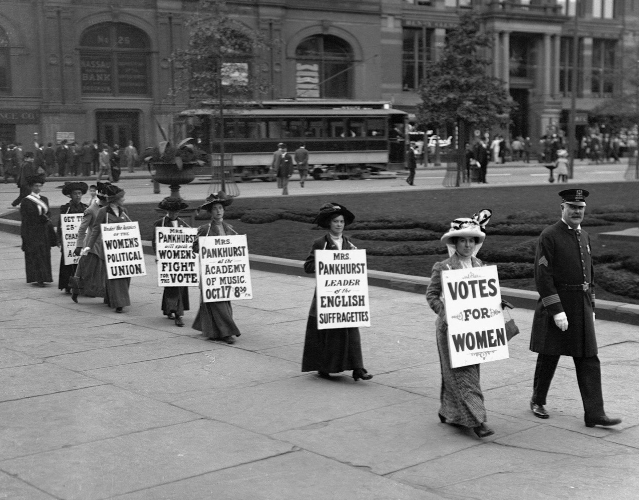   Suffragettes parade down Bedford Avenue in Brooklyn wearing signs reading "Votes for Women". 
