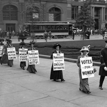 Suffragettes parade down Bedford Avenue in Brooklyn wearing signs reading "Votes for Women"