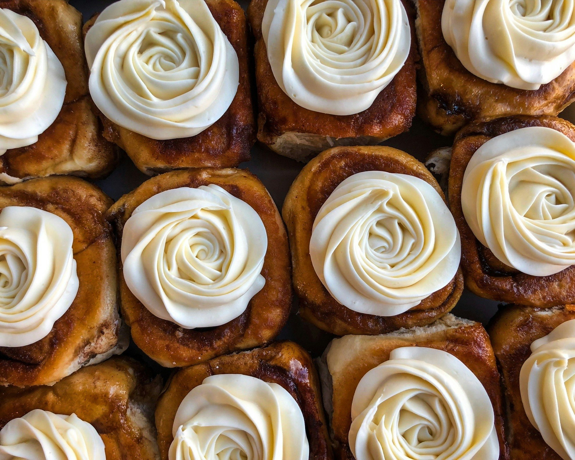 Rows of cinnamon rolls with cream cheese spiraled topping