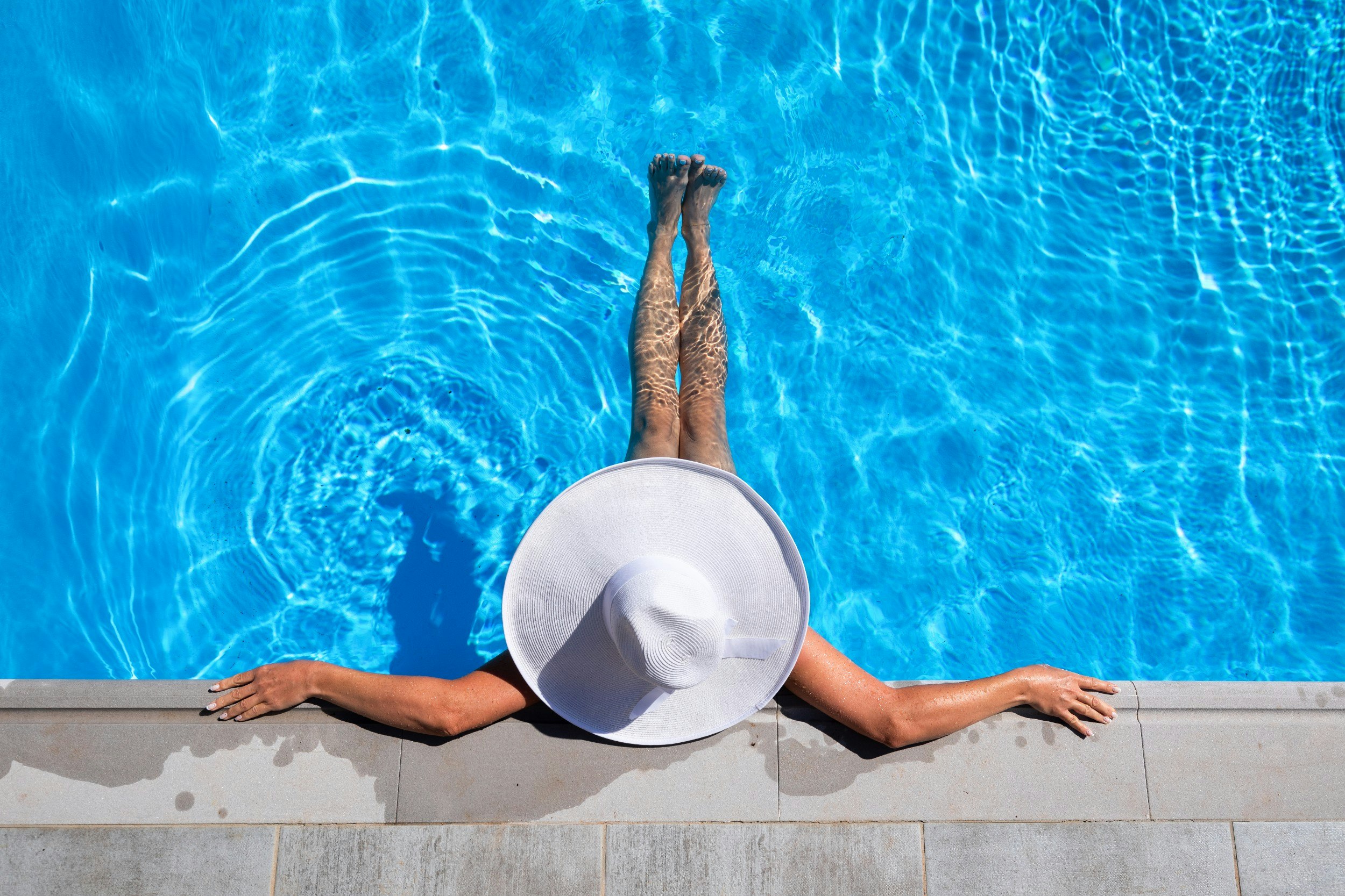 A woman in a pool wearing a sunhat