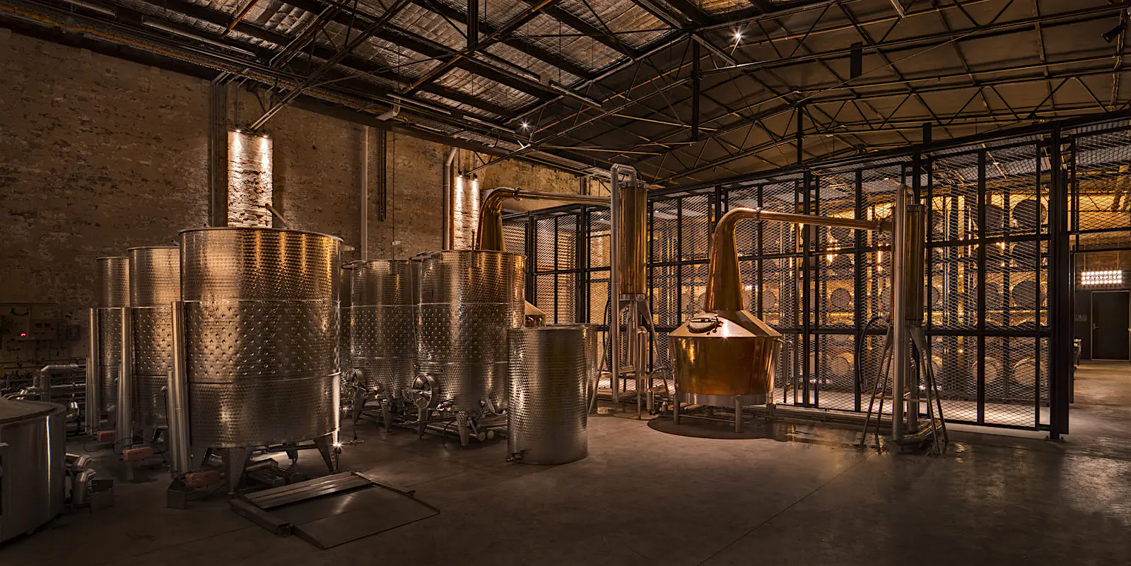 Sydney-gin_Archie_Rose_Distillery.jpg The warmly lit interior of Archie Rose distillery, Sydney, showing a small copper still and large steel washbacks.