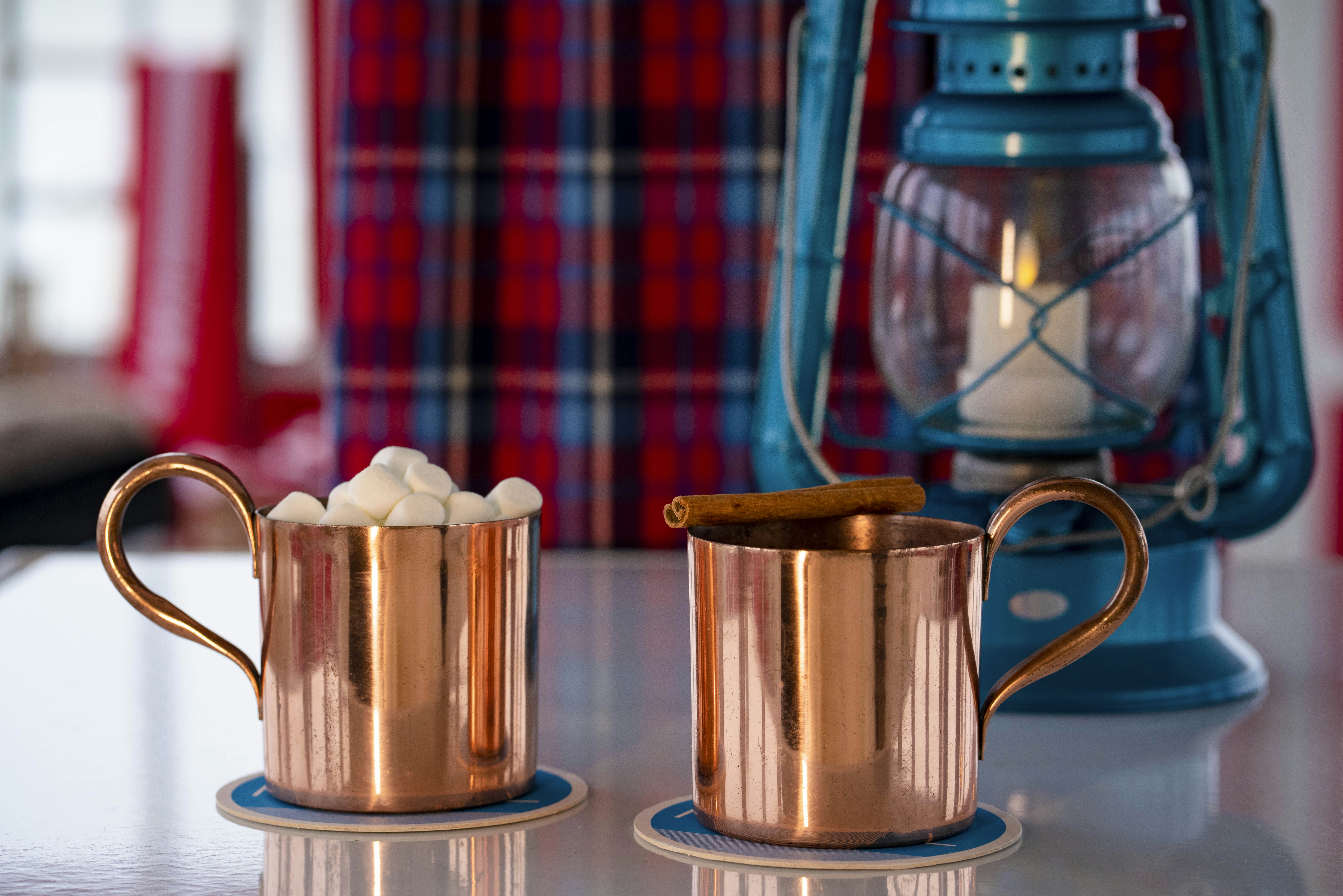 Two copper mugs, one with marshmallows and the other with a cinnamon stick on top, at the TWA Hotel Runway Chalet at The Pool Bar