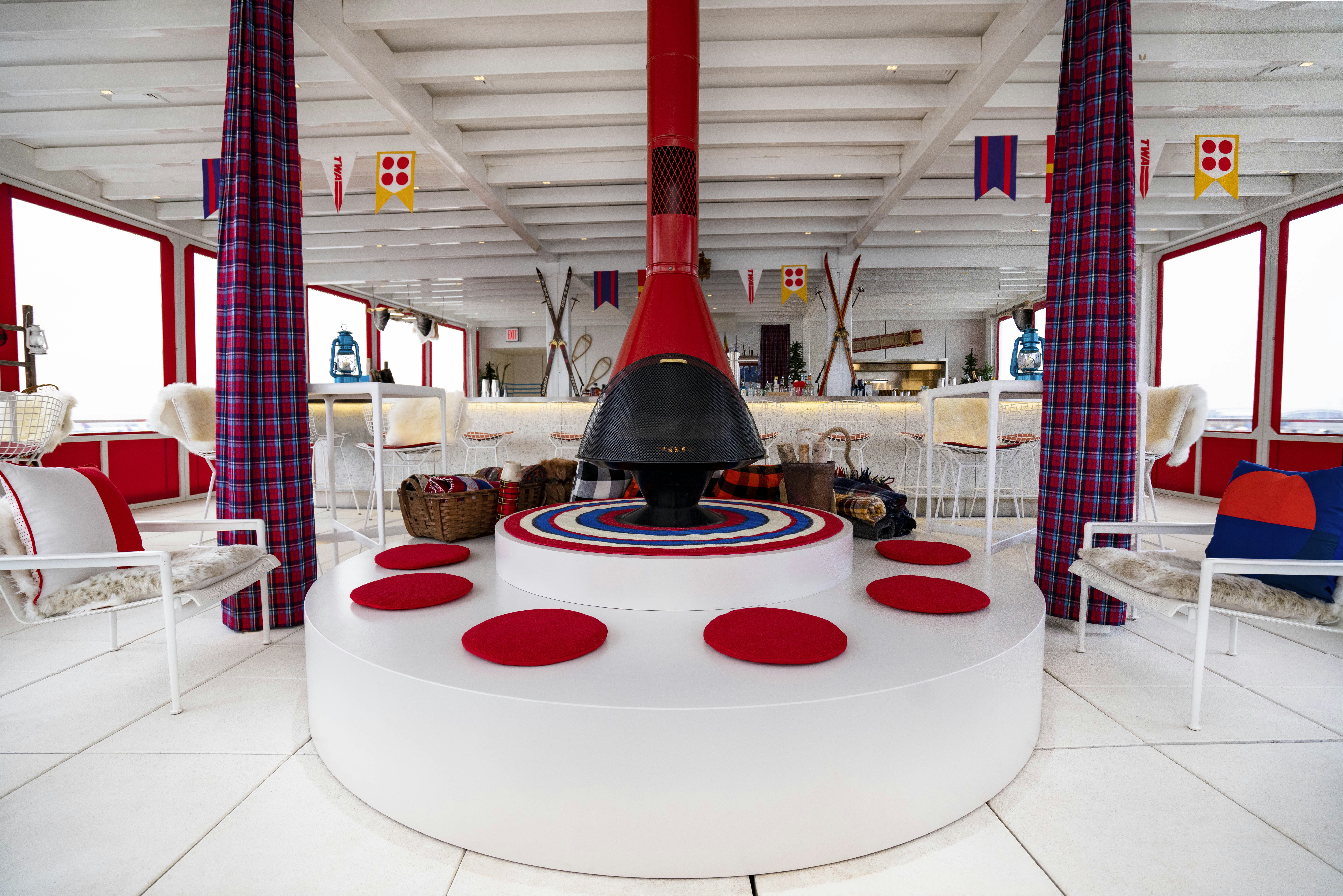 TWA Hotel Runway Chalet at The Pool Bar interior - red fireplace on a round white foundation with red cushions