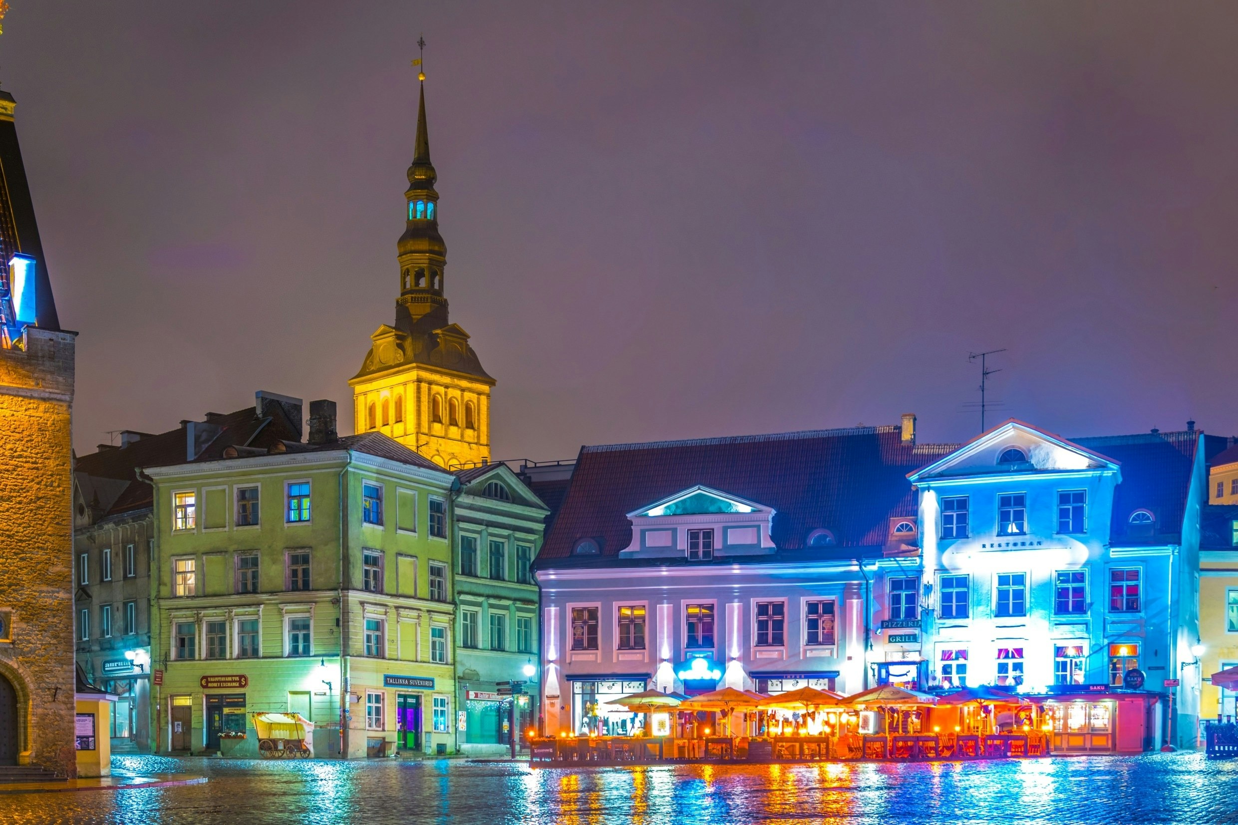 Pastellfärgade gamla byggnader på ett torg i Tallinn på natten.