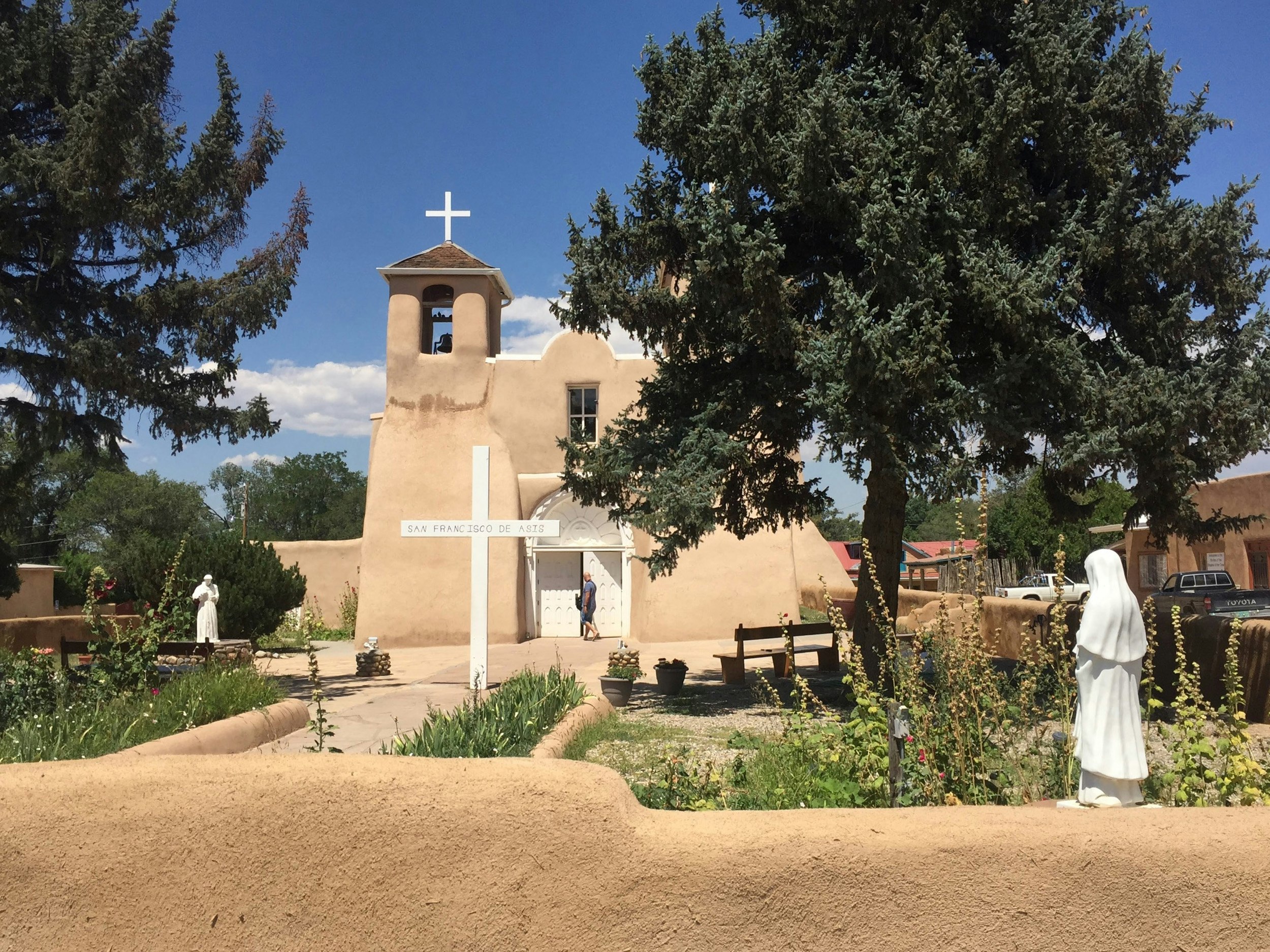 A pretty courtyard surrounded by tan mud walls is seen on the High Road to Taos