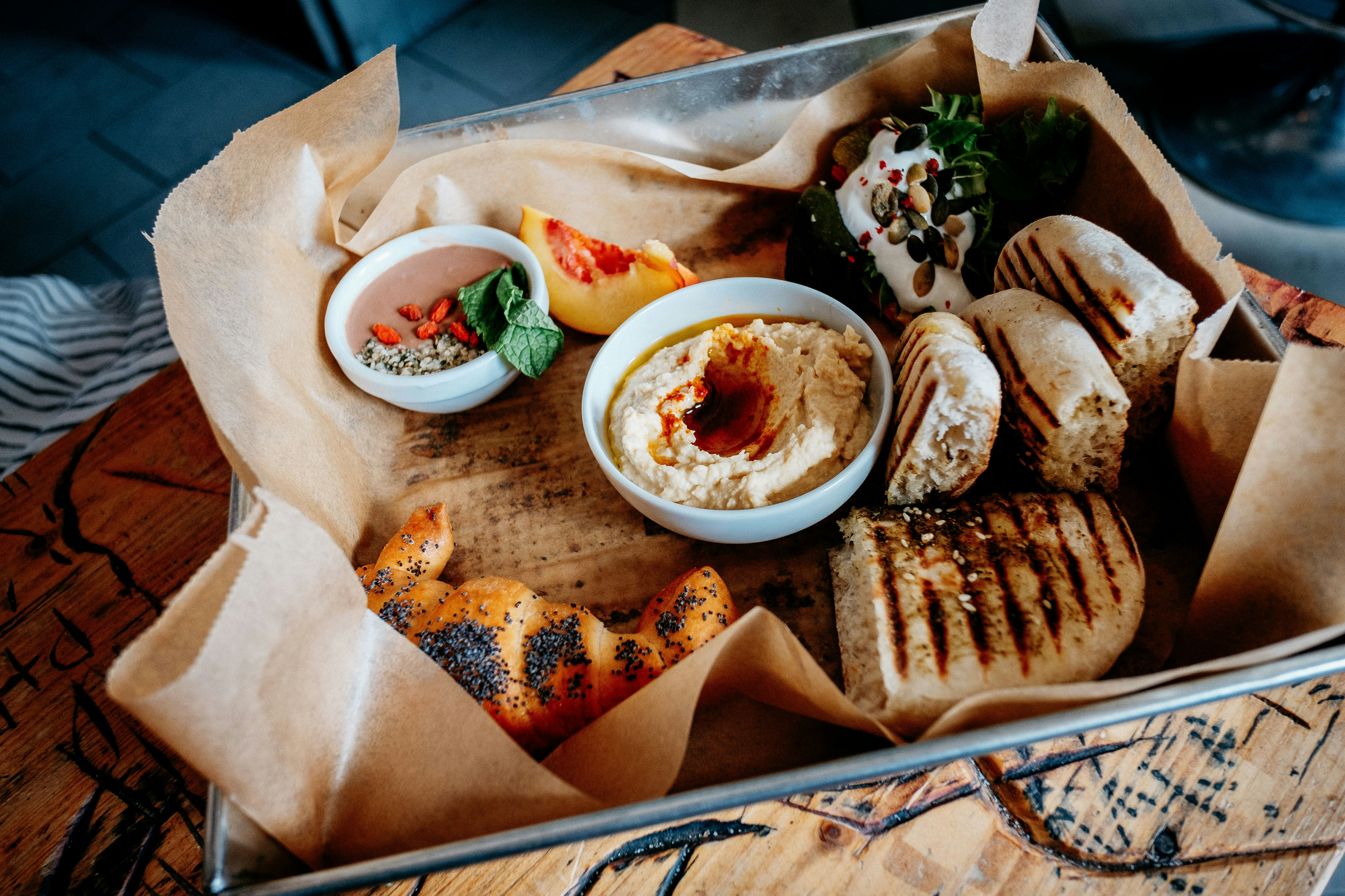 Grillat bröd, hummus och andra dippar arrangeras i en metallbricka klädd med bakplåtspapper som en del av Taste of Prague Food Tour.