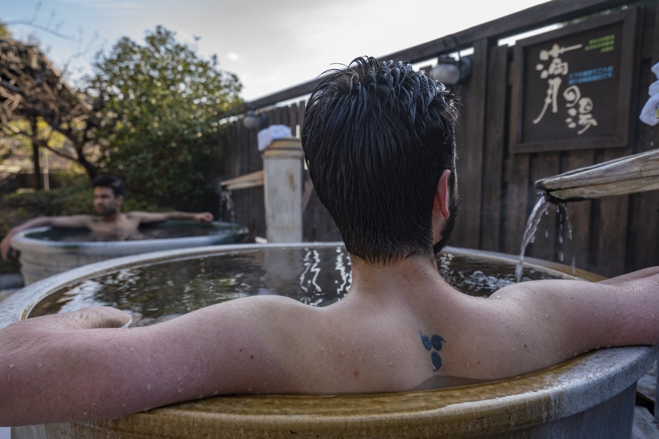 Tattooed man bathing in outdoor onsen