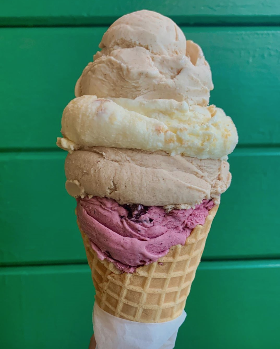 A closeup of a four-scoop ice cream cone featuring Peach Butter, Honey Cornbread, Apple Butter and Aroniaberry Blueberry