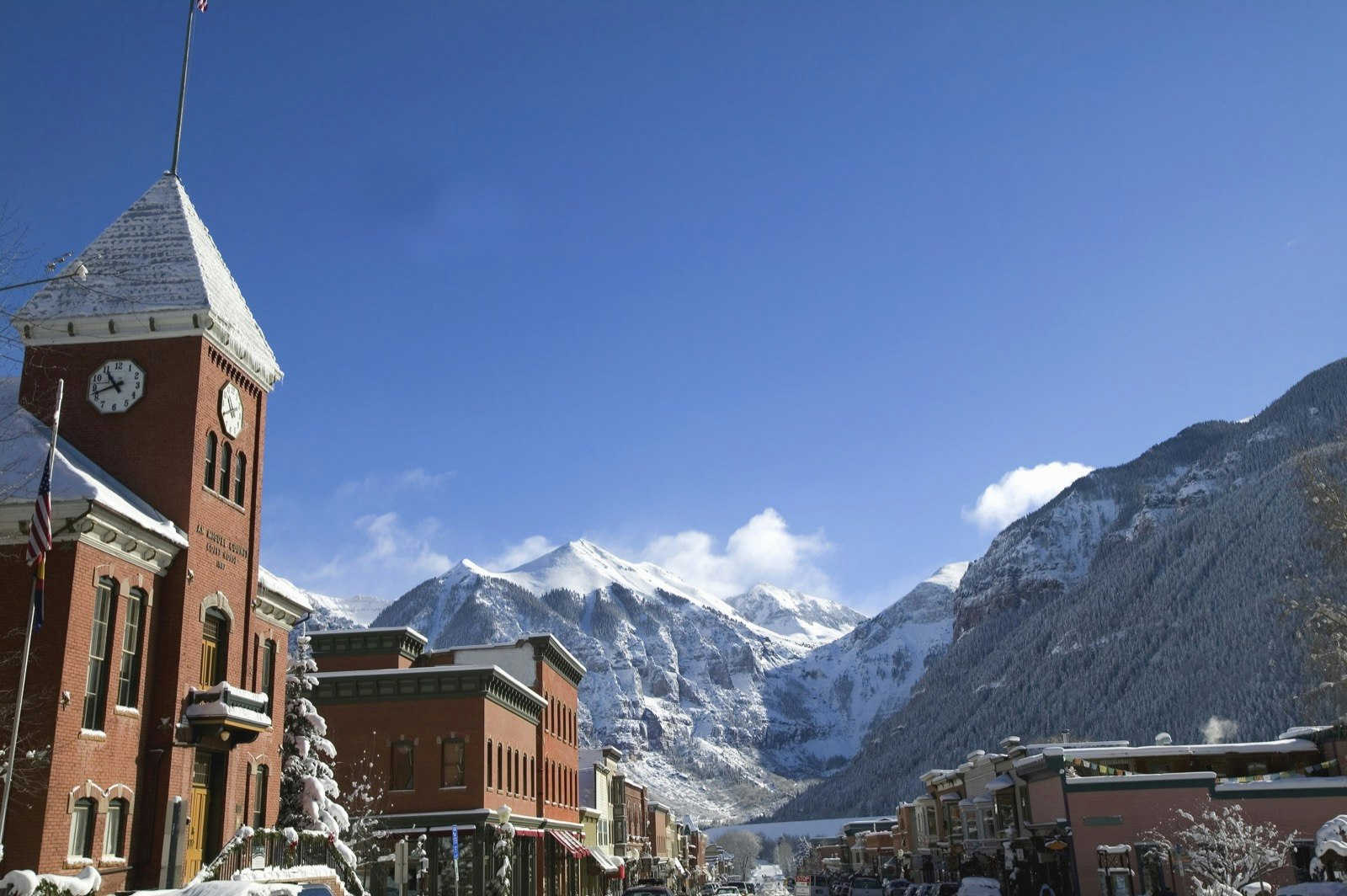A huge snow covered mountain stretches beyond the historical buildings of main street Telluride, Colorado