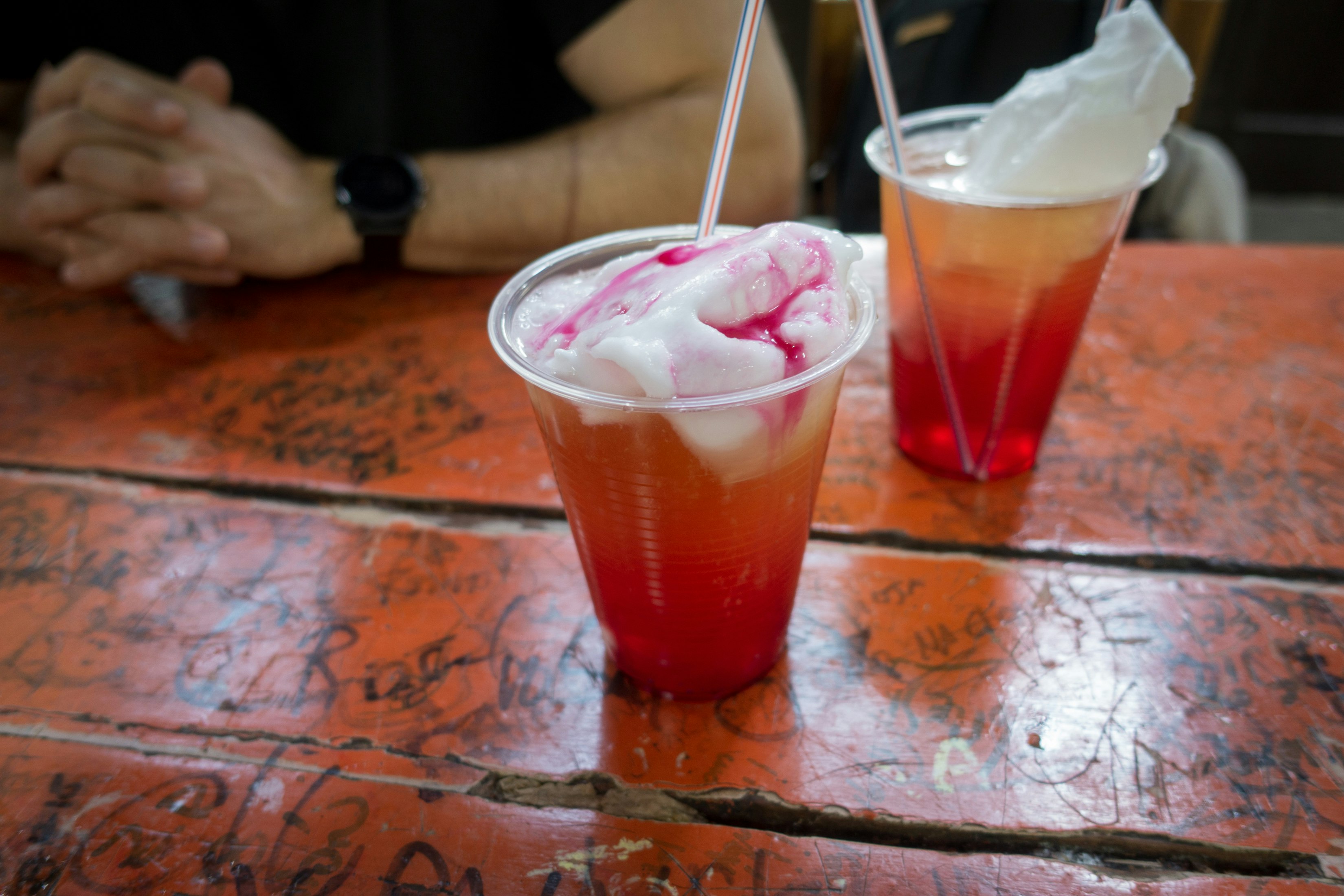 A pair of drinks topped with ice cream sit on a wooden table