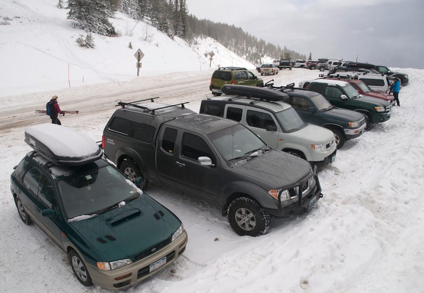 En rad parkerade bilar sträcker sig så långt ögat når på en snötäckt väg