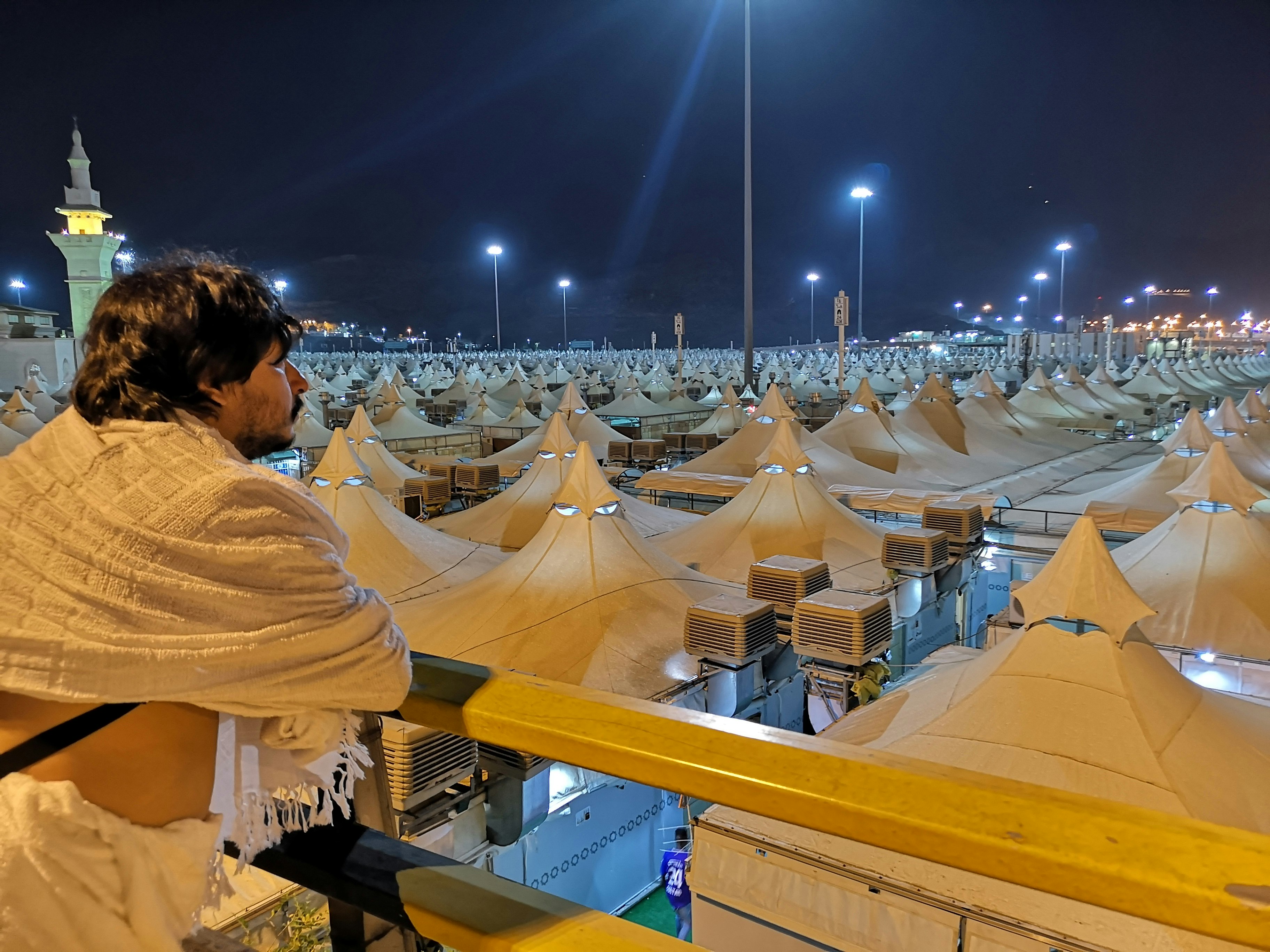 A man dressed in white robes looks out over the organised tents in Mina.