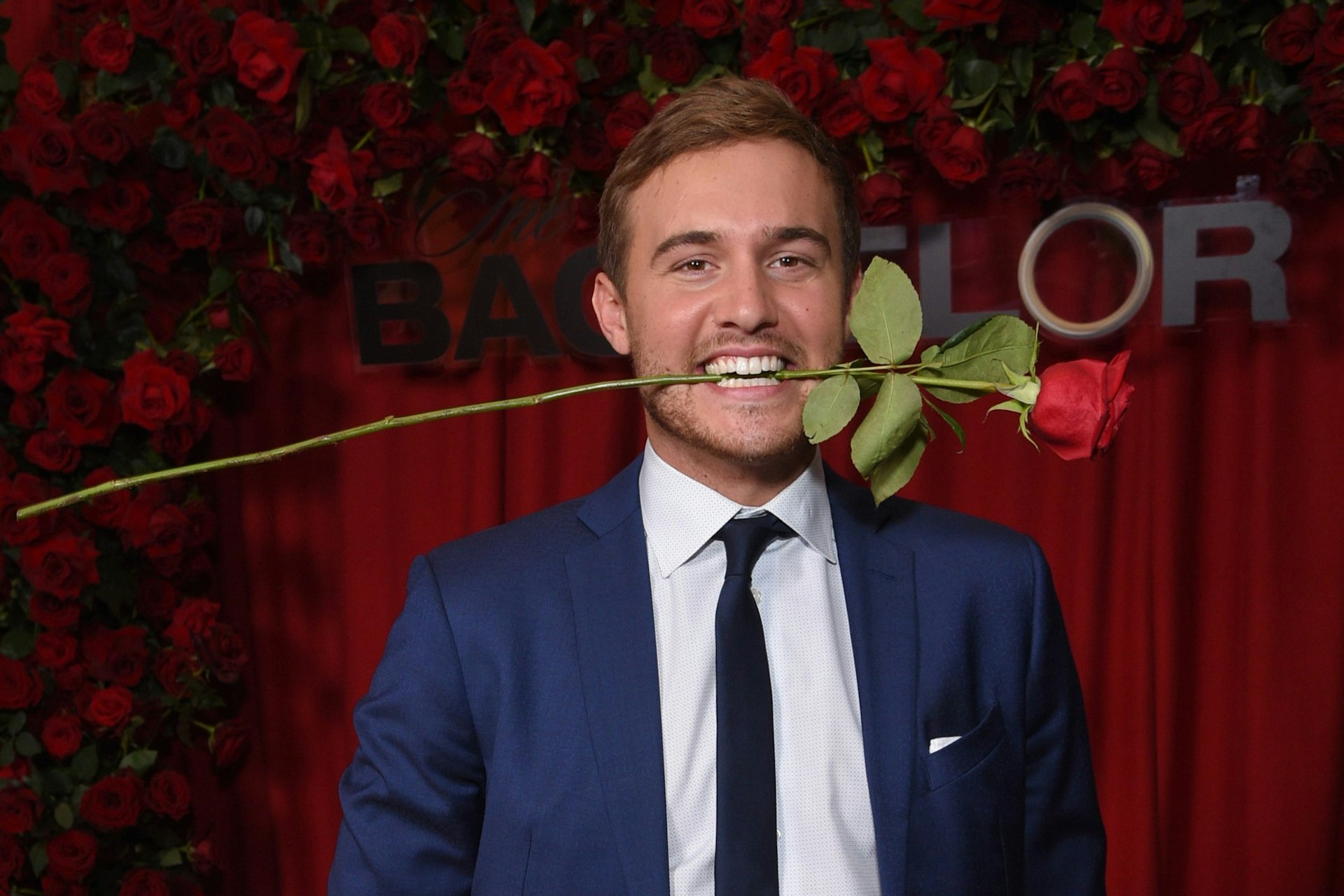 The Bachelor star with a rose in his mouth