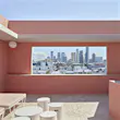 Brisbane's skyline pictured through a large rectangle gap in a pink wall on The Calile's rooftop