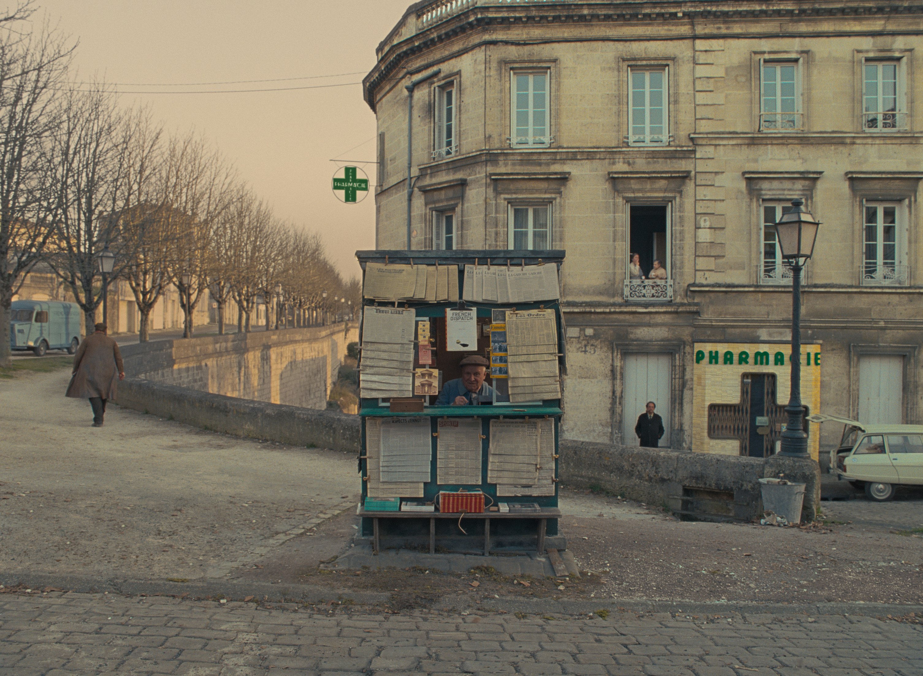 A man pops his head out of a newspaper kiosk in a still from the film The French Dispatch