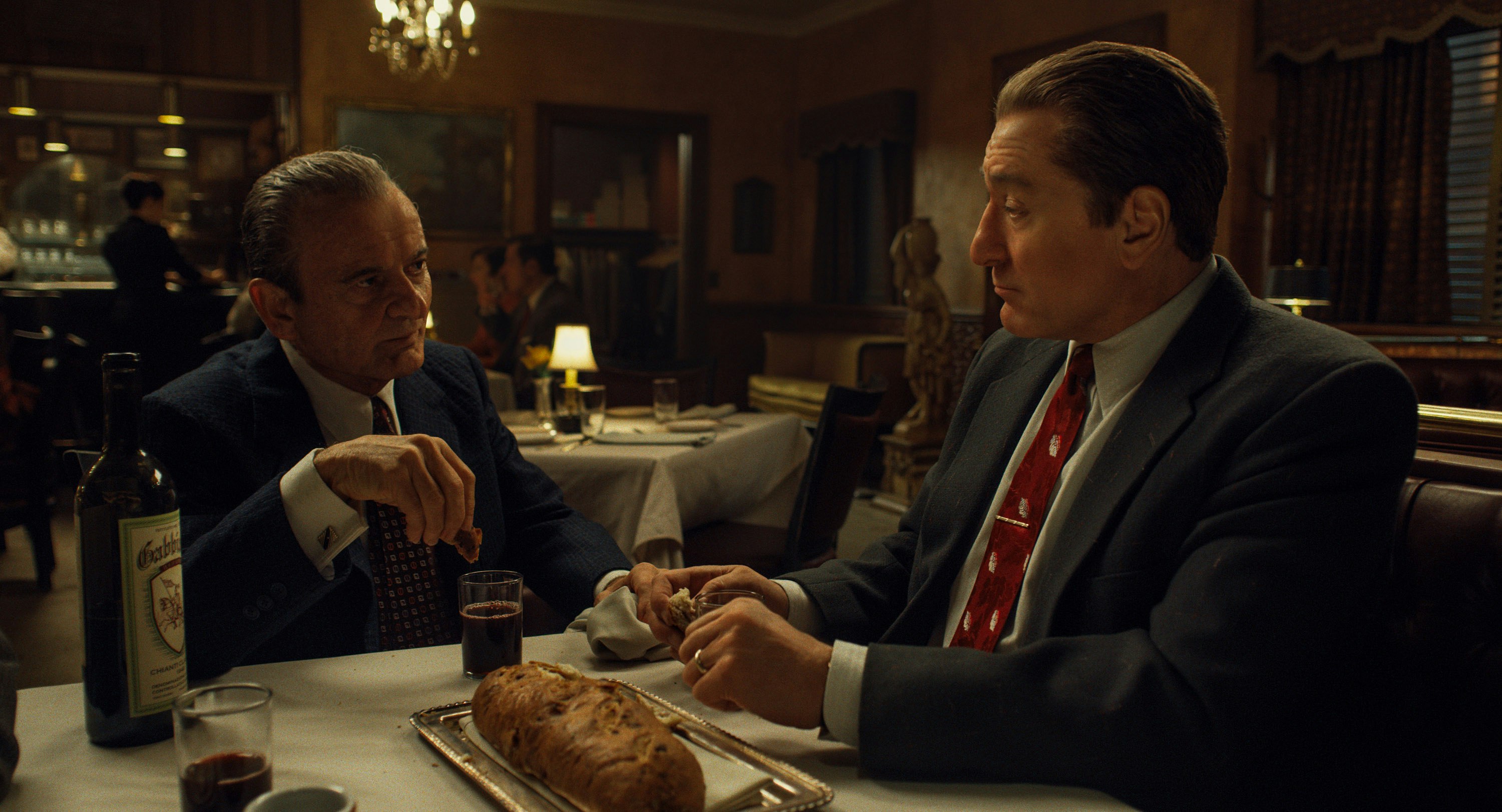 Actors Joe Pesci and Robert De Niro are sitting having dinner in a dimly-lit restaurant in a scene from 'The Irishman'.