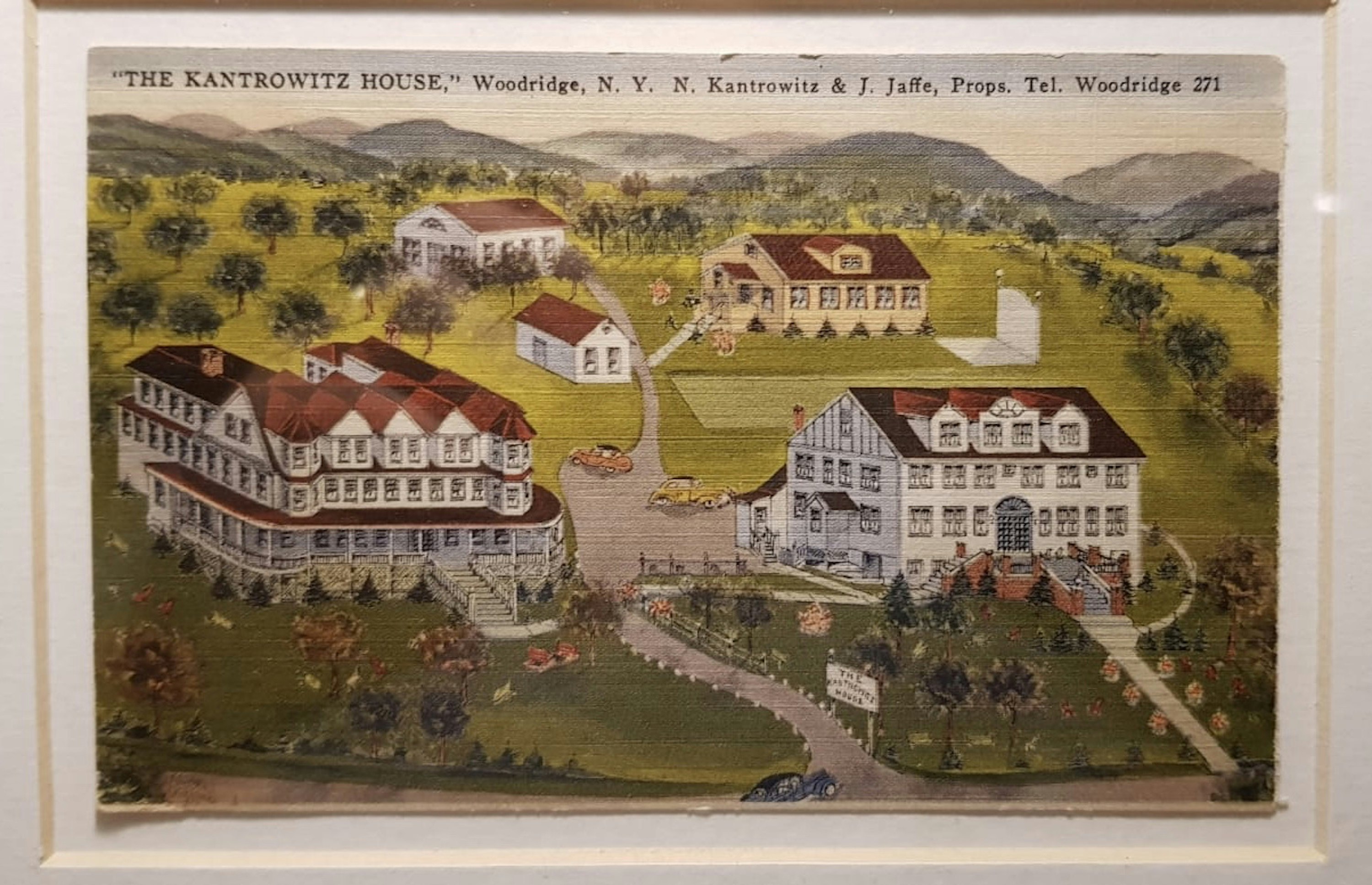 A vintage illustration of the Kantrowitz House resort, depicting five white buildings with red roofs and long driveways set amongst grassy hills with mountains in the background.