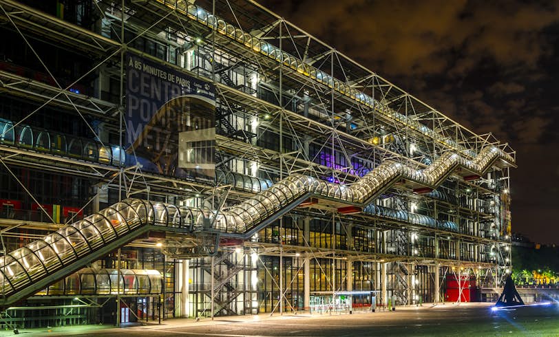 A night view of the Pompidou Centre. A stair that resembles a tube is visible going up the side of the building. 